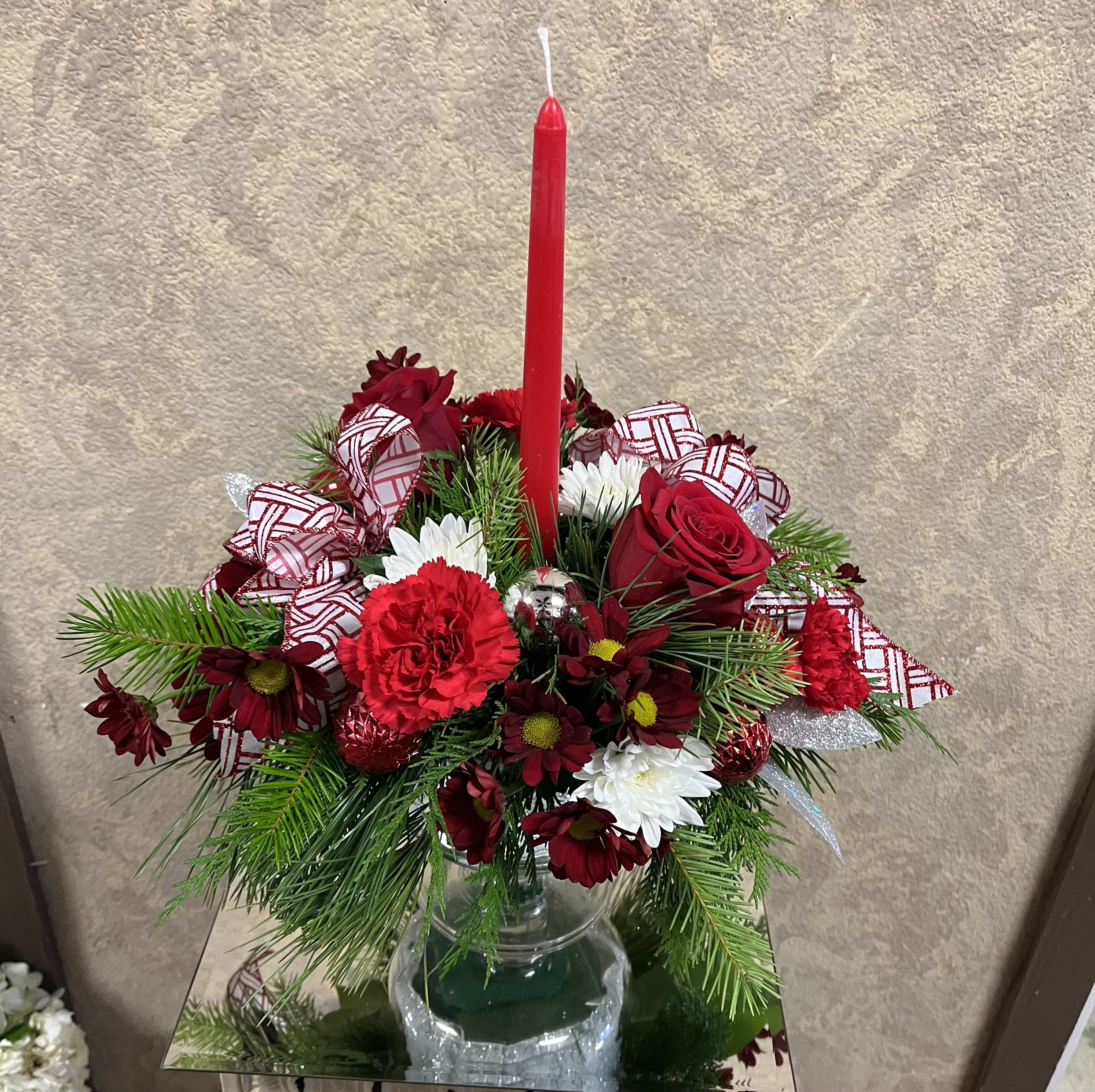 A Delightful Christmas Centerpiece - Recipe: Red Roses, Carnations, Daisies, White Chrysanthemums and pine leaves, in a tall platter vase with stem that includes a candle, ribbon and ornaments. Seasonal: Holiday Design View: All Facing View Photo shown: Standard