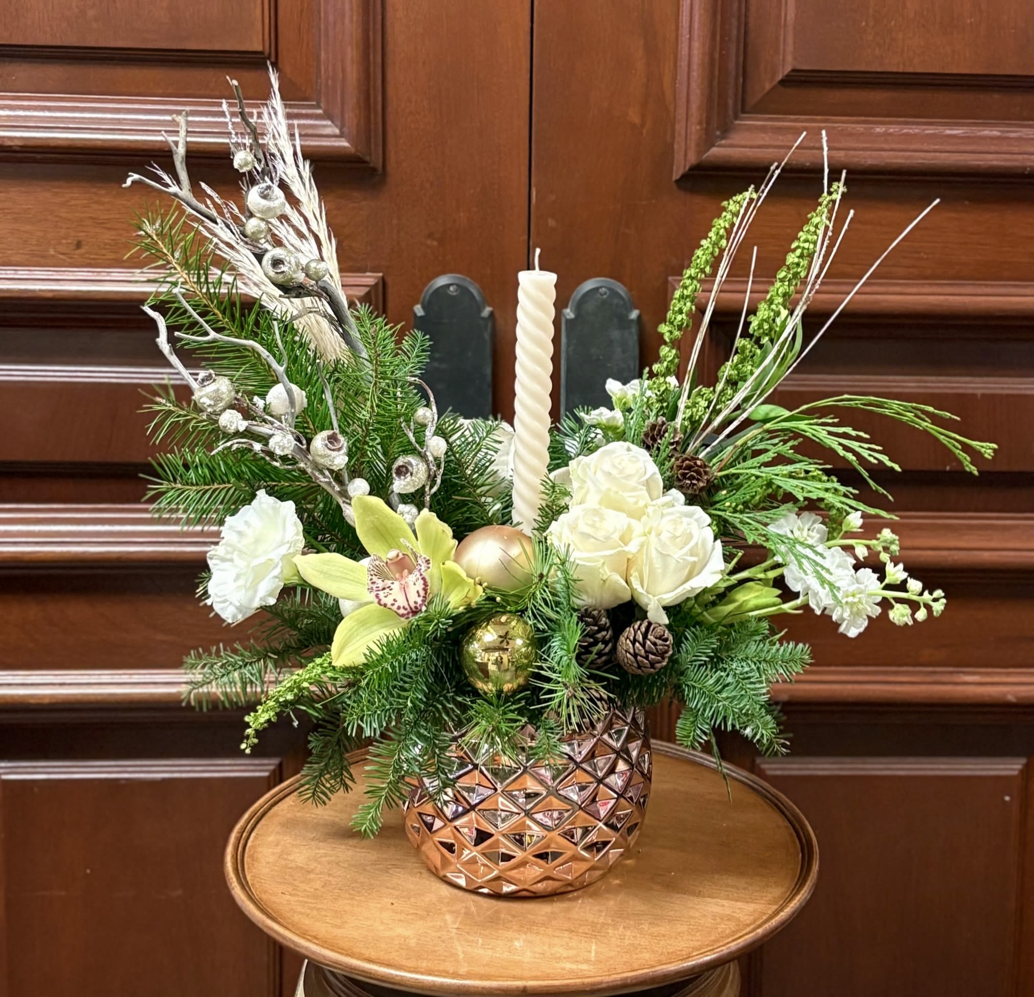 Jolly Good Time - Recipe: White Lisianthus, White Stock, Green Amaranthus, Green Orchids, White Roses, Pine Greens, Silver/White branches, Holiday ornaments and accents in a rose gold vase. Seasonal: Winter Orientation: Front Facing View Photo shown: Standard 