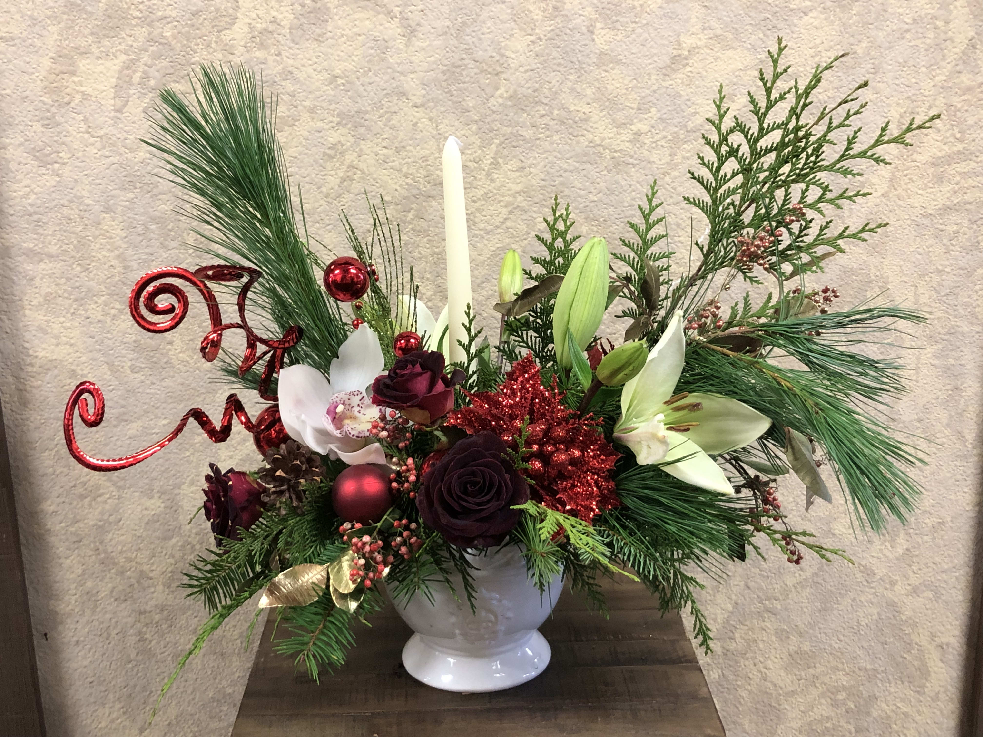 Silky Christmas Centerpiece - Traditional Christmas arrangement with white asiatic lilies, red roses, white orchids, pines, silks, ornaments and candles in a white plaster.