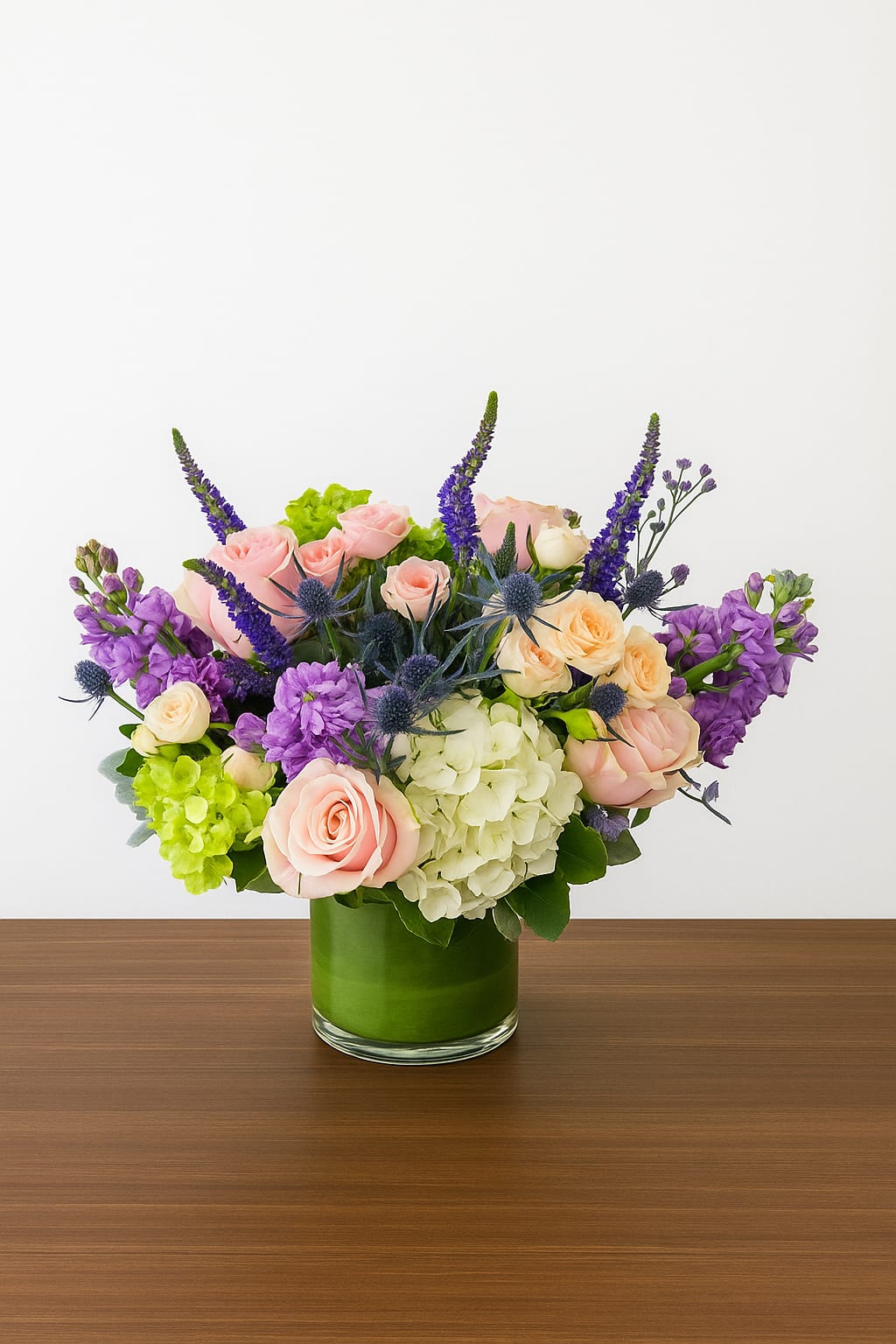 Pretty Woman - Graceful, feminine, and effortlessly romantic — Pretty Woman captures timeless beauty in every bloom. This stunning arrangement features soft blush roses, lavender stock, creamy hydrangeas, and accents of delicate thistle and green hydrangea for a fresh, modern touch. Designed in a sleek glass vase wrapped with lush greens, it evokes charm and sophistication.  Perfect for anniversaries, birthdays, or simply to make someone feel special, Pretty Woman brings a touch of classic romance to any space.