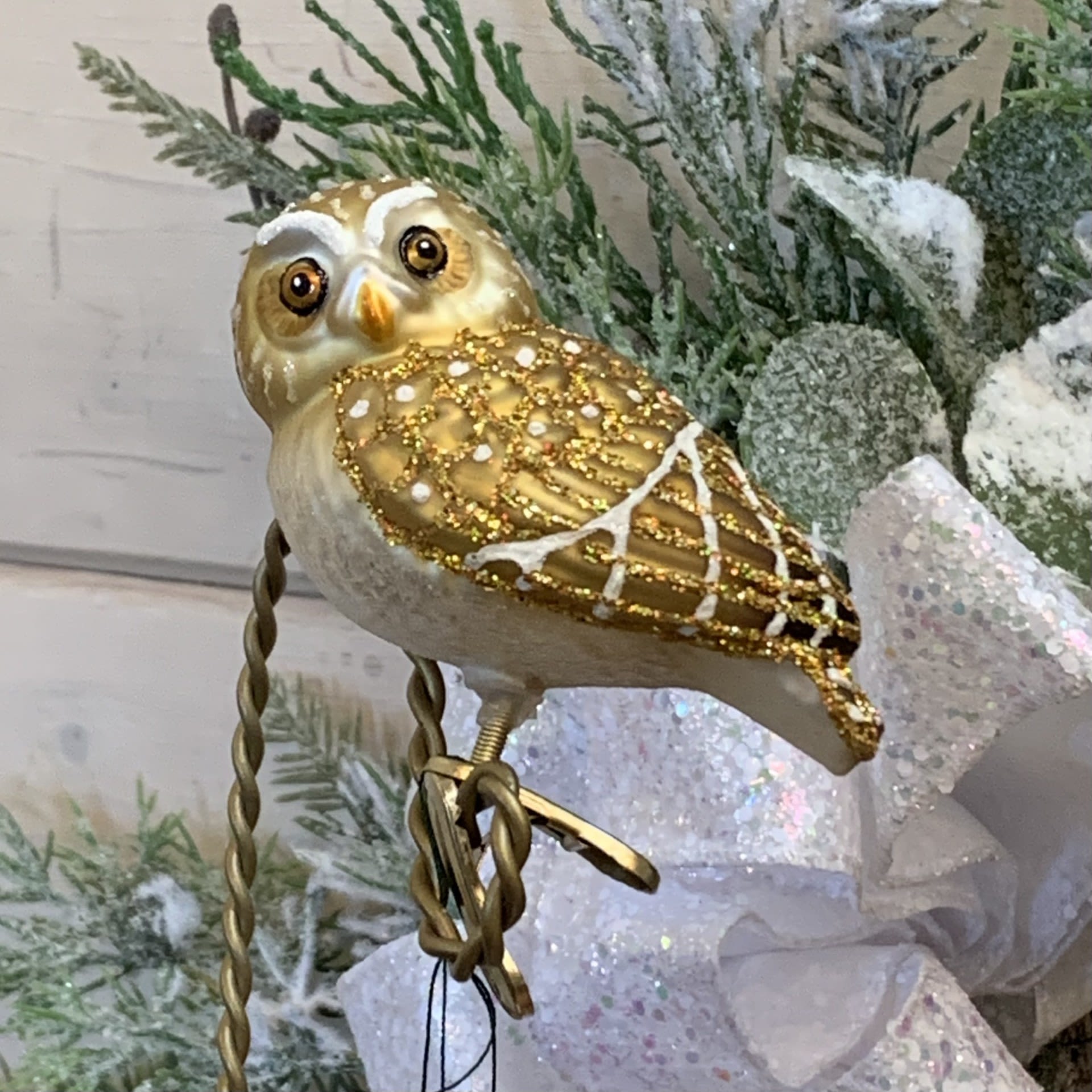 Pygmy Owl Clip on Ornament - Owls are symbols of wisdom because they look so serious and thoughtful. Since they can see in the dark, they represent seeing through the darkness of ignorance. Despite its small size, the Northern Pygmy Owl is quite fierce and will attack prey or drive off intruders several times its own size.  Approximately 2&quot; tall and 3&quot; wide.  Each figurative glass ornament produced by Old World Christmas is hand crafted in age-old tradition using the same techniques that originated in the 1800s. Molten glass is mouth-blown into finely carved molds made exclusively for Old World Christmas, before a hot solution of liquid silver inpoured inside. The ornaments are then hand-painted and glittered in a series of labor-intensive steps to achieve our beautiful creations.  Wreath and Tree Branch not included.   For more ornaments please check out our store at 3882 Mayberry Dr Ste A, Reno, NV 89519   