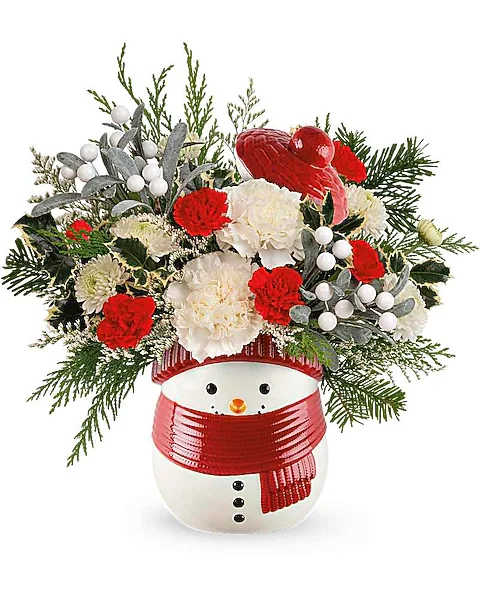 Teleflora's Snowy Delight Bouquet - Charming and festive, this classic Christmas gift presents a delightful ceramic snowman treat jar filled with joyful holiday blooms, adding a touch of seasonal magic to any space. Celebrate the holiday season with this festive arrangement of white carnations, miniature red carnations, and white button spray chrysanthemums, adorned with variegated holly, noble fir, and cedar. The Snowy Delight Bouquet is beautifully delivered in the Frosty Wishes Jar, adding a touch of winter charm to any setting.