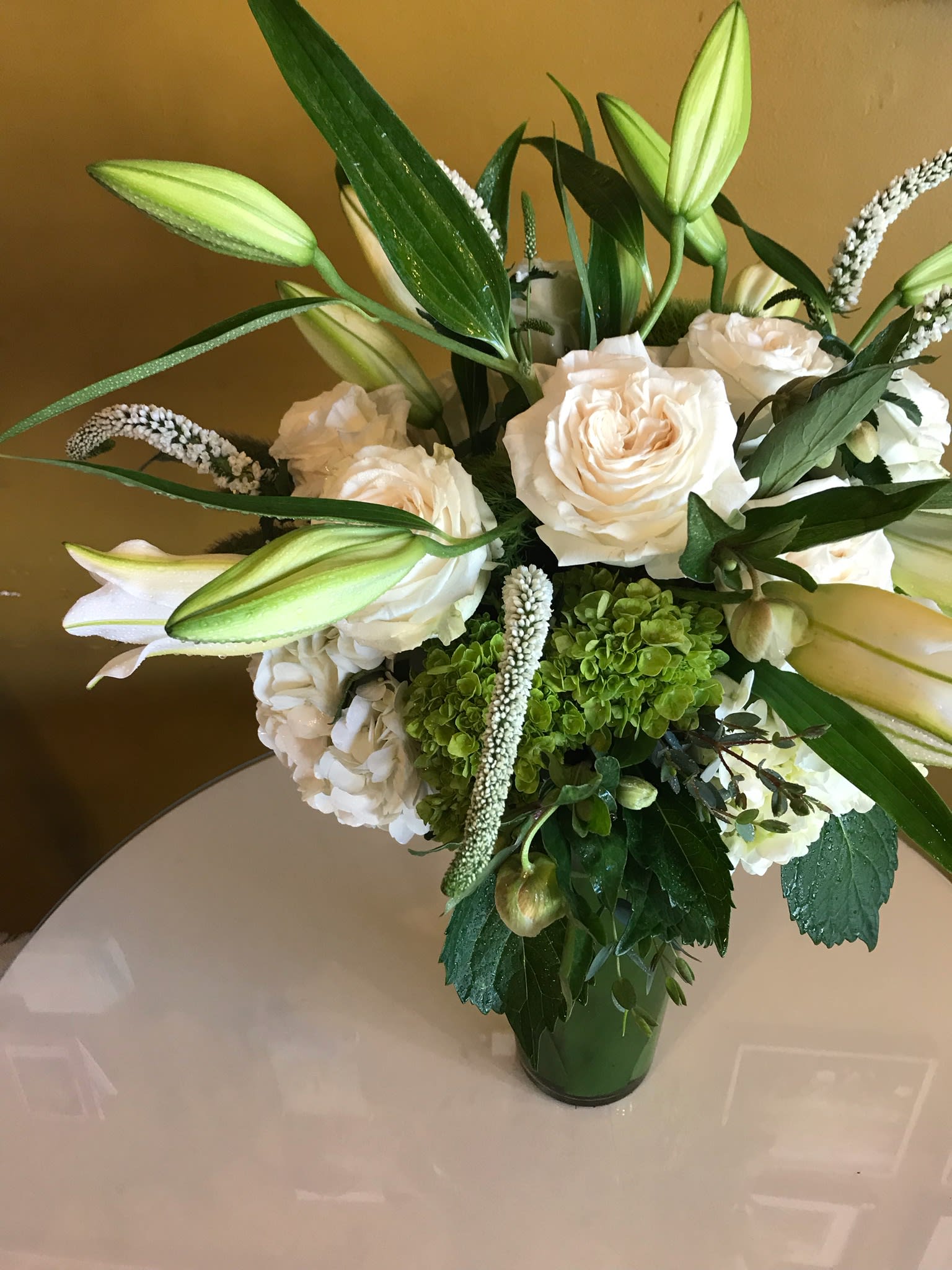 Roses, lilies, hydrengia, veronica - Elegant holiday or sympathy flowers arranged in leaf lined vase.