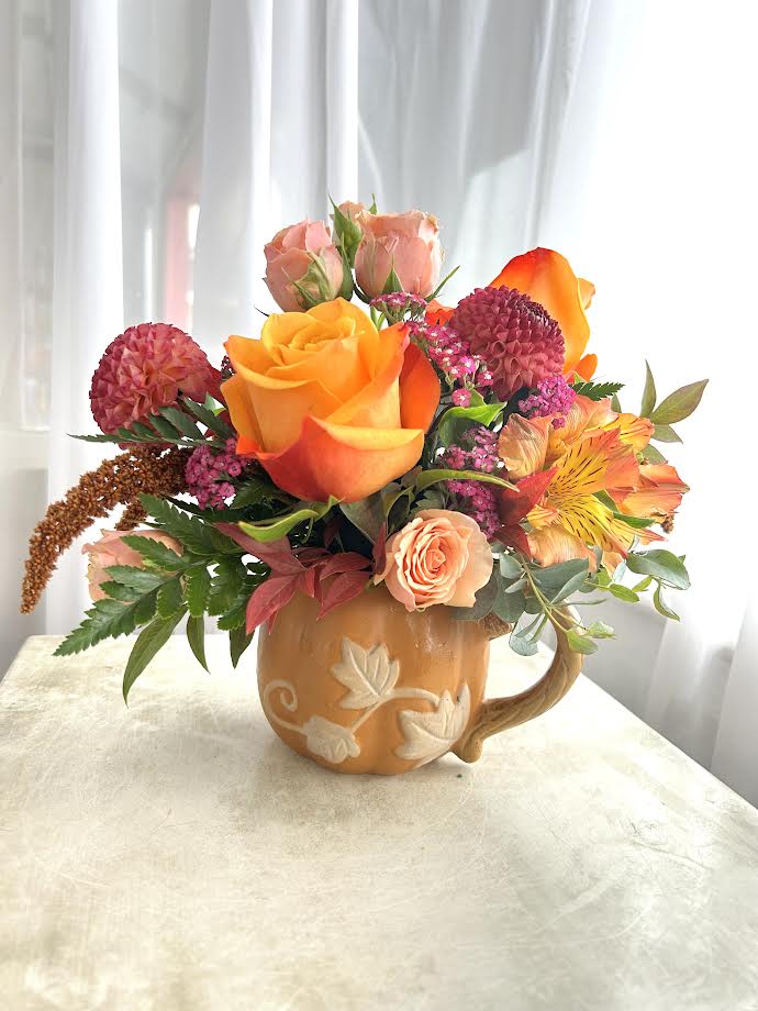 Fresh off the Vine - A vibrant fall arrangement featuring a variety of seasonal blooms in fall tones, designed in a reusable harvest pumpkin mug. Perfect for a warm mug of cider, or for coffee drinkers, a cup of our Jetty Java coffee. As always, all designs are subject to substitution. 