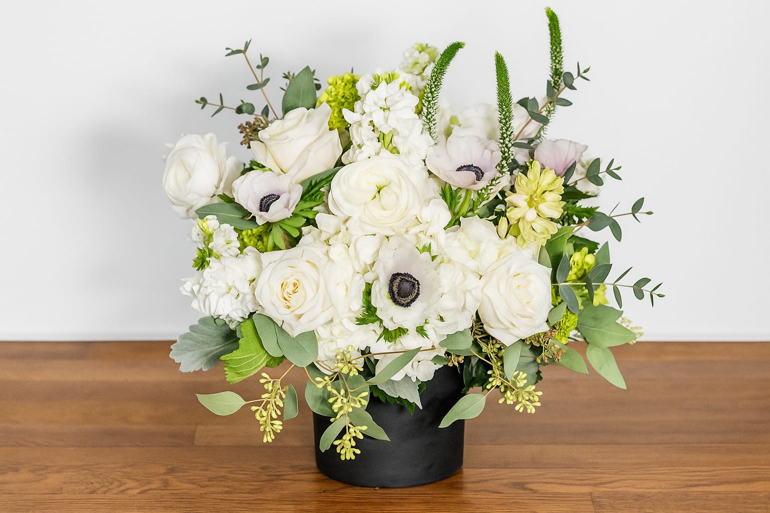 Diamonds and Pearls - “Diamonds and Pearls” is an elegant white floral arrangement featuring lush roses, ranunculus, and anemones accented with soft greenery. Designed in a sleek black vase, this timeless bouquet brings refined luxury to weddings, special occasions, or modern home décor. Perfect for those who adore classic white blooms with a touch of sophistication — available for delivery in San Francisco.