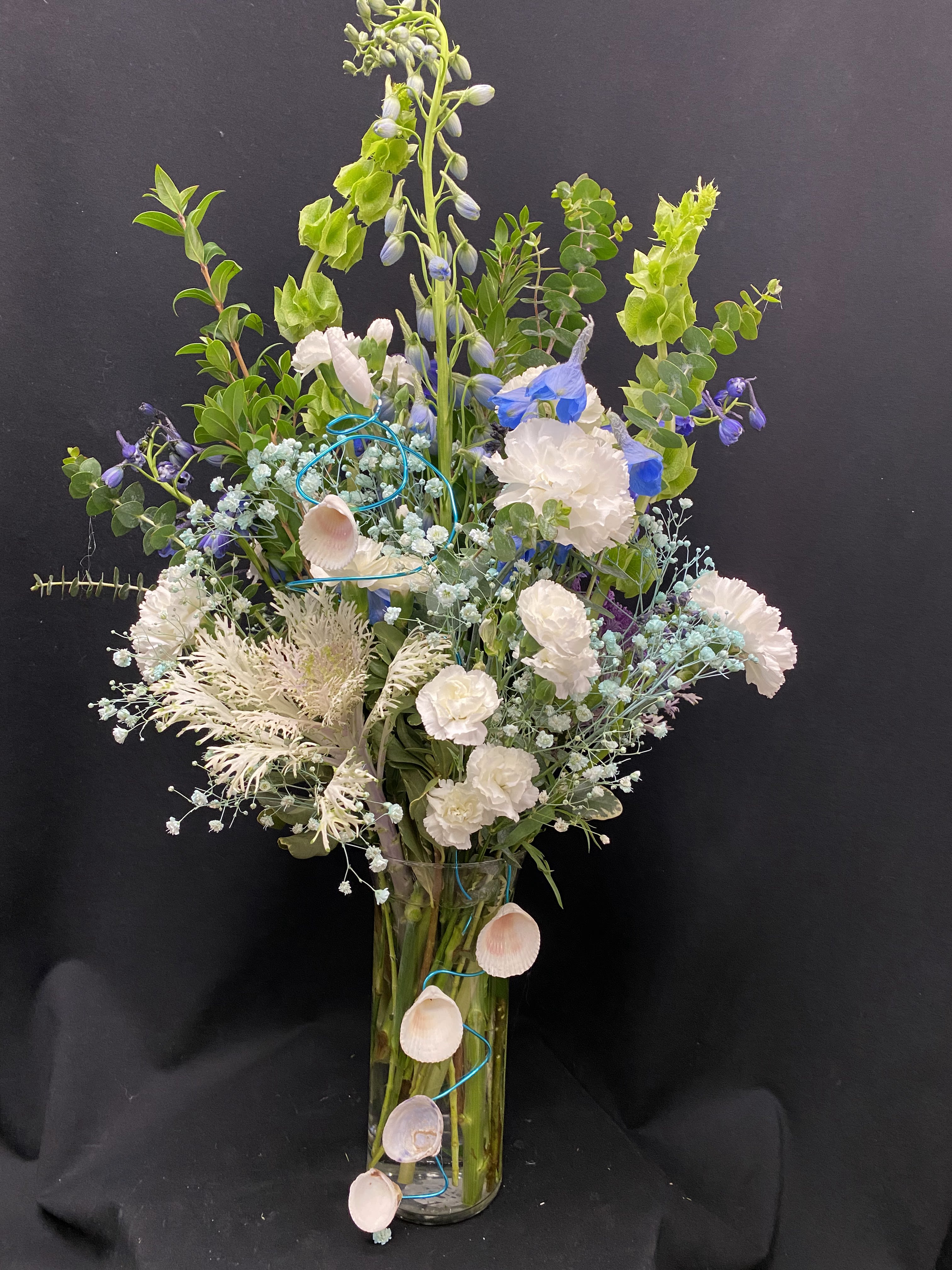 By the sea - Vase Ornamental cabbage, light blue delphinium, bells of irleand, white carnations and mini carnations, turquois baby's breath, sea shells and turquois whire