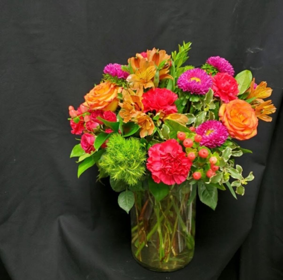 Happy for you - Vase with orange, green, red and hot pink flowers, spray roses, asters, carnations, hypericum berries, dianthus and mixed greens