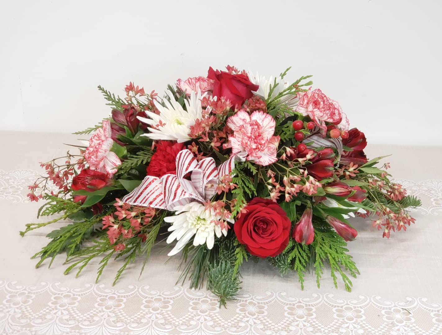 Merry Centerpiece - Merriment abounds with this favorite centerpiece of Ol' St. Nick. Makes a wonderful gift of joy and merriment for everyone on your list. Please allow for flower substitutions. Festive theme will be maintained. Approximately 18&quot; wide. 