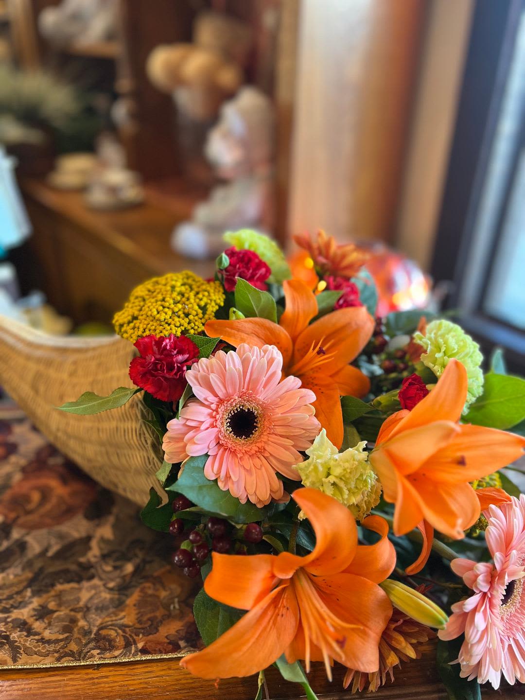 Gratitude in Bloom Cornucopia  - Orange asiatic lilies paired with soft pink gerber daisies, green carnations, yarrow, hypericum berries, red elegance, and cushion poms to convey all of your gratitude and thankfulness this Thanksgiving season. 