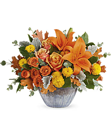 Golden Bounty Centerpiece Arrangement - Make the season shine with this golden fall bounty of roses and lilies, arranged in a gorgeous oven-to-table ceramic bowl. It's finished with an eye-catching artisanal glaze in shades of steel blue, the perfect mix of pretty and practical! Approximately 17 inches wide and 12 inches tall for the Standard size. 