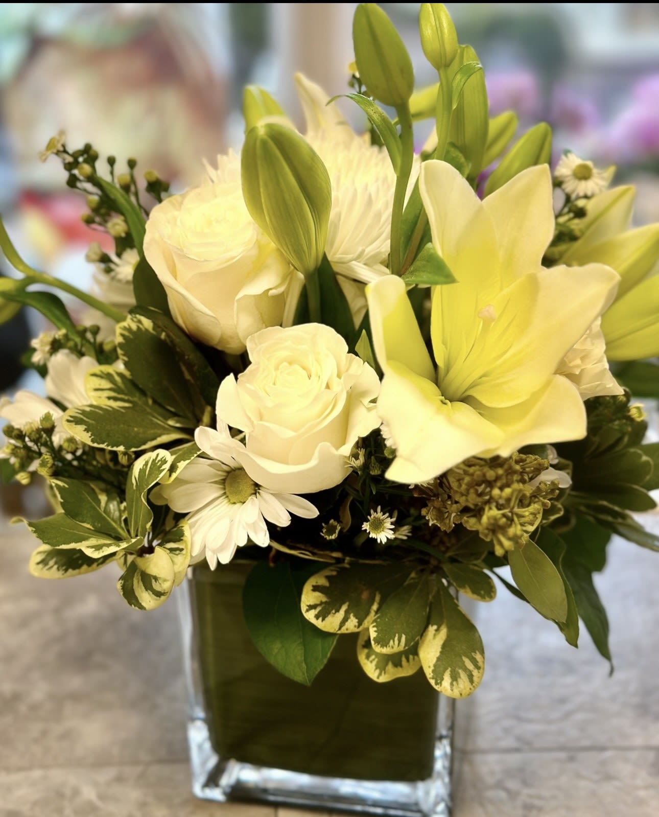 HOPE SQUARED BOUQUET - A GLASS CUBE FILLED WITH WHITE ROSES, WHITE LILLIES, ASTERS, WHITE DAISIES AND GREENS A SYNCERE STATEMENT OF CARING