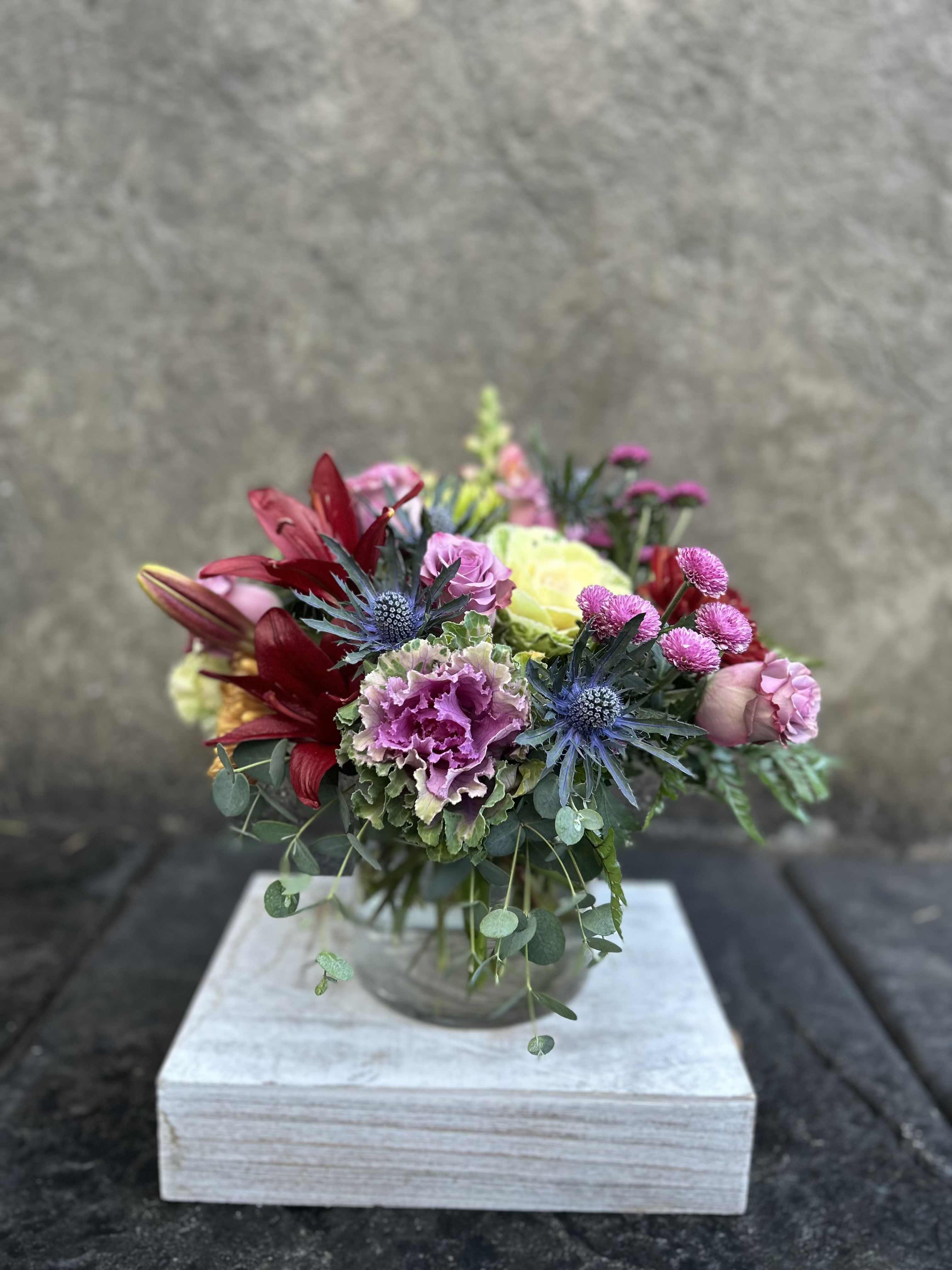 Kale Salad - Decorative Kale , burgundy asiatic Lillies, chrysanthemums, lavender roses, snapdragons, eryngium, button poms, eucalyptus, and other greenery.   *Reasonable substitutions may be made due to floral availability. Will have overall look and theme.