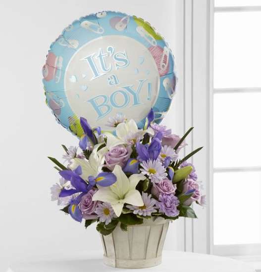 Baby Boy Balloon Bundle - Blooming with sweet love to congratulate the new family on their darling baby boy! Lavender roses, blue iris, lavender carnations, lavender daisies, white Asiatic lilies and lush greens are beautifully arranged in a round whitewash basket. Presented with a Mylar balloon declaring, It is A Boy!, this incredible flower arrangement is the perfect welcome for their new addition.  *Please note we may replace some stems in your arrangement for color or flower variety. While we always do the best to match the picture shown, sometimes different vases may be used. Any substitution made will be similar to the original design and be of equal or greater value.