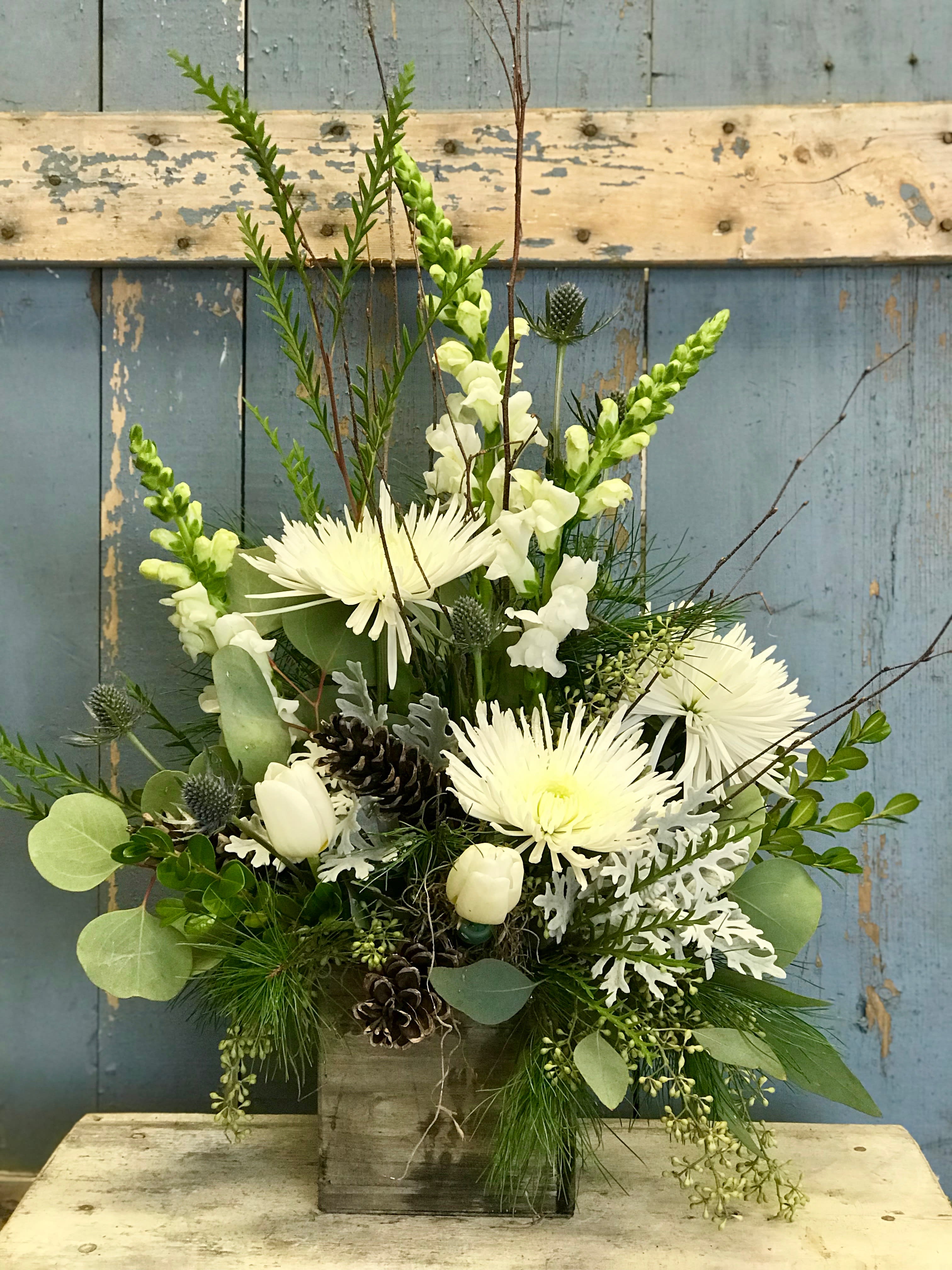A Silent Night - This classic white and green arrangement is accented with blue thistle, birch tips and pine cones and arranged in a 4x4&quot; wooden box. (Deluxe version will be in a 5x5&quot; box.)