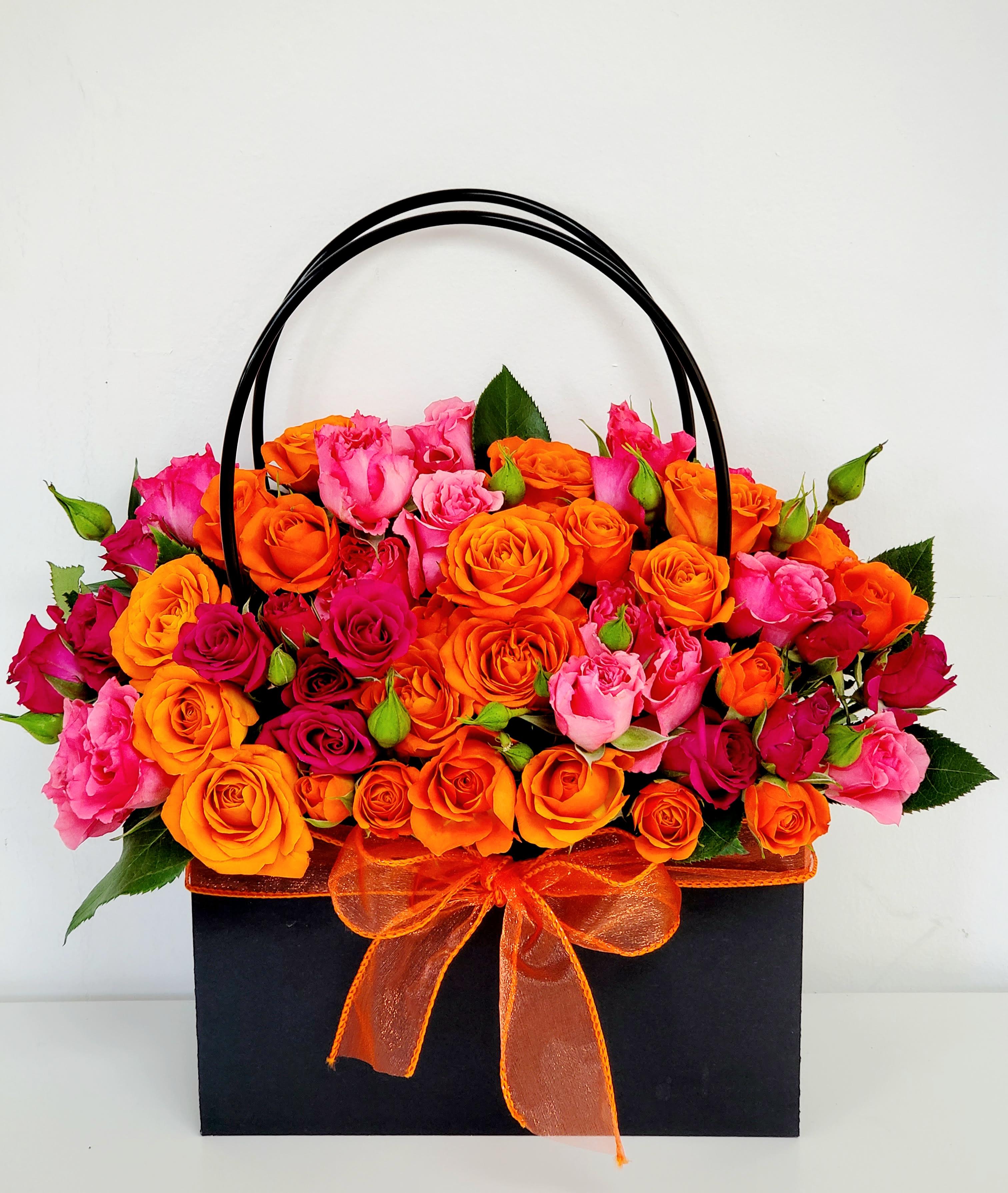 Bag of Vivid Blooms - The Bag of Vivid Bloom is a striking, contemporary arrangement designed for dynamic gifting. It features a concentrated mass of delicate spray roses, bursting with energetic color. Fiery orange and electrifying hot pink blossoms are blended to create a vibrant, joyful display. Presented beautifully in a stylish, handled bag, this vivid bouquet is ready to carry sunshine and passion wherever it goes. PREMIUM SIZE ONLY 15&quot;W by 13&quot;H
