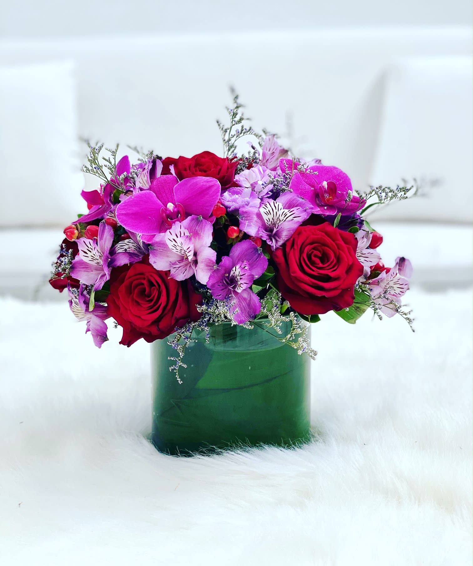 Deja Vu ™ - This arrangement is a lush blend of elegance and vibrance, combining rich red roses with vivid fuchsia orchids and delicate alstroemeria. Set in a sleek green vase, it strikes the perfect balance of romance and sophistication—ideal for both modern spaces and heartfelt gifting.