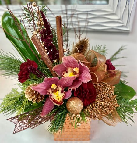 Toasted Cinnamon - Elegant orchids arranged into a lovely copper toned keepsake container with burgundy blooms, fragrant holiday greenery, and copper accents.