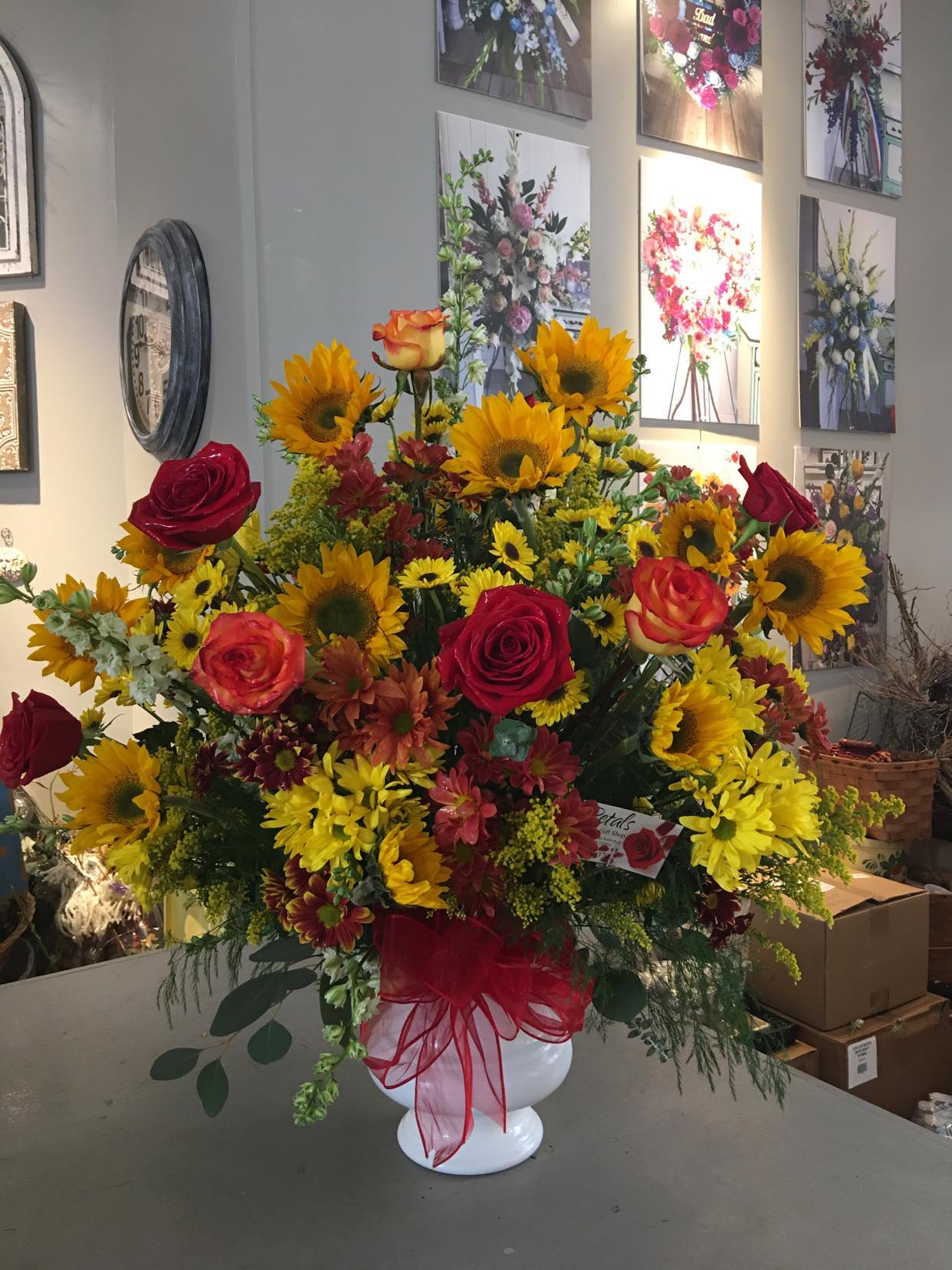 Crisp Colors of Fall XL Urn Arrangement by Petals  - The Crisp Colors of Fall Urn Arrangement offers a beautiful and dignified tribute for any funeral service or memorial. The family is sure to appreciate this generously sized display, featuring a vibrant assortment of fresh chrysanthemums, cheerful sunflowers, and classic roses. We kindly request 24 hours' notice to prepare this piece to perfection. For same-day delivery, please call me directly at 401-828-0701, and I will be happy to verify flower availability for you. Thank you, Cheryl. 