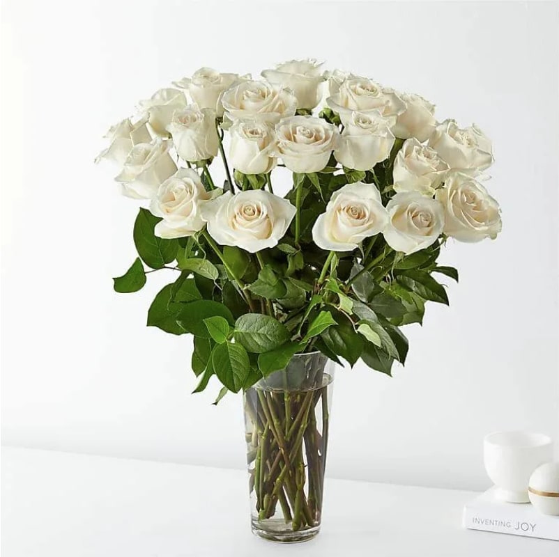 Passion Of The White Roses-Two Dozen - A joyful gesture of love and affection, this chic arrangement of one dozen pure white roses with fresh greens is a special surprise on any occasion. 24 white roses are arranged with salal and delivered in a clear vase.