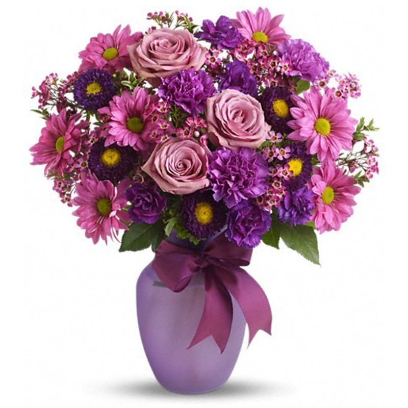  Love and Laughs Bouquet - Lavender roses and daisy spray chrysanthemums, purple carnations, miniature carnations, and pink waxflower are delivered in a lavender or purple vase.     One sided arrangement.