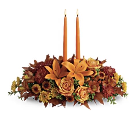 Teleflora Family Gathering Centerpiece - Graciously gather your family around the warm glow and classic autumn colors of this stunning Thanksgiving centerpiece. A lush variety of burnt orange blooms are gathered under a pair of tall, graceful candles - perfect for decorating your Thanksgiving dinner table, entryway or hearth. Fall flowers include orange roses, orange asiatic lilies, dark orange alstroemeria, bronze button mums, yellow cushion mums, rust cushion mums, green oregonia and green huckleberry. Accented with oak leaves and two orange taper candles. Orientation: All-Around  SUBSTITUTION POLICY – Always deliver the freshest flowers! Please note the bouquet pictured reflects our original design.  If the exact flowers or container in this arrangement are not available, our local florists will create a beautiful bouquet with the freshest available flowers.