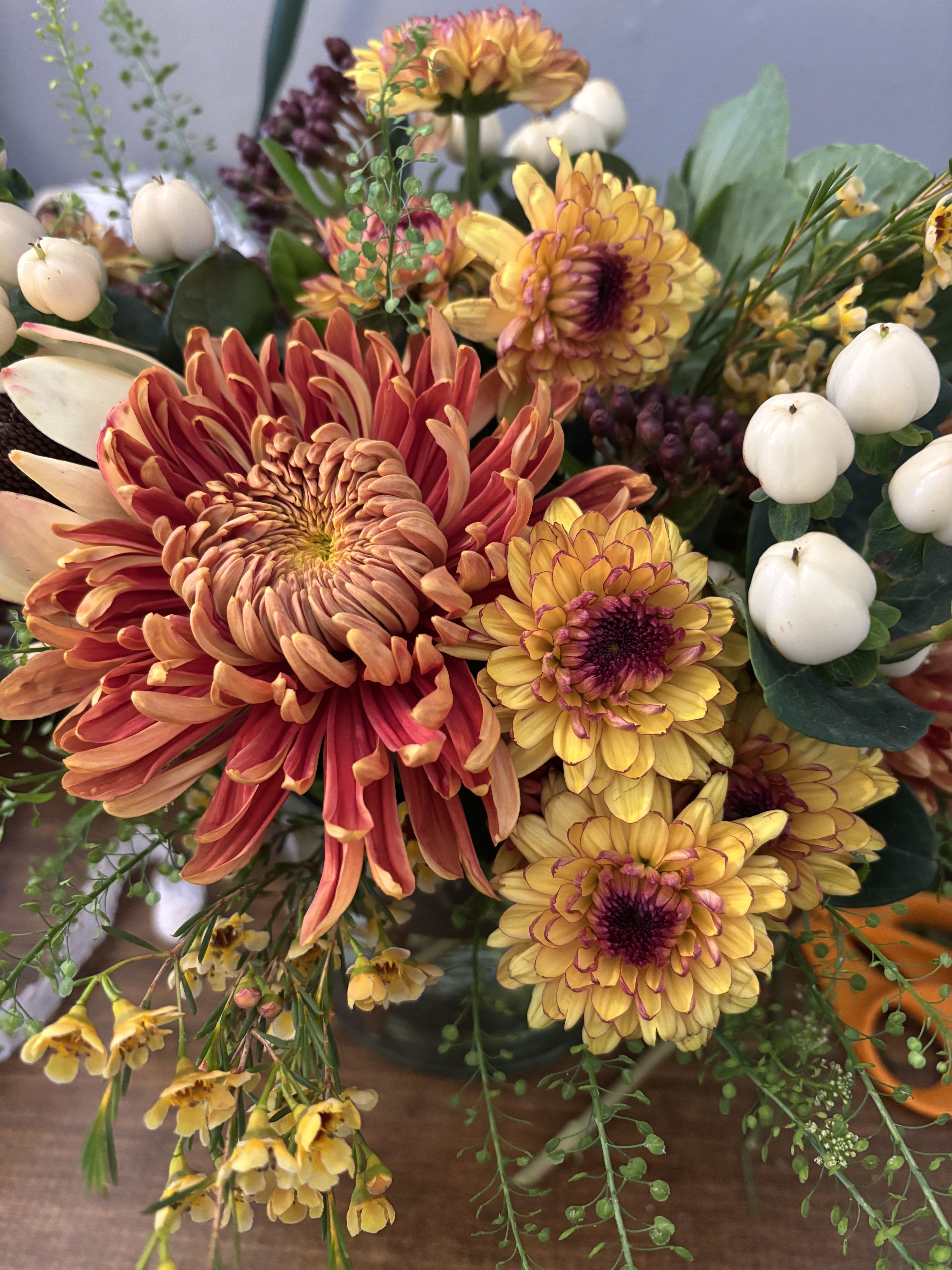 Autumn Spice - Just as traditional as stuffing on Thanksgiving this classic centerpiece is going to have a nostalgic feel to it. Filled with mums, carnations  berries and lush greenery. Flowers’s will be designed in a woven basket. Perfect for a dining table, kitchen island or coffee table.   Approximately 8x8 inches tall and wide  Every effort will be made to recreate your chosen design. Please note that from time to time due to product availability and quality we may need to make substitutions. We will make sure to keep the original design in mind when making substitutions.