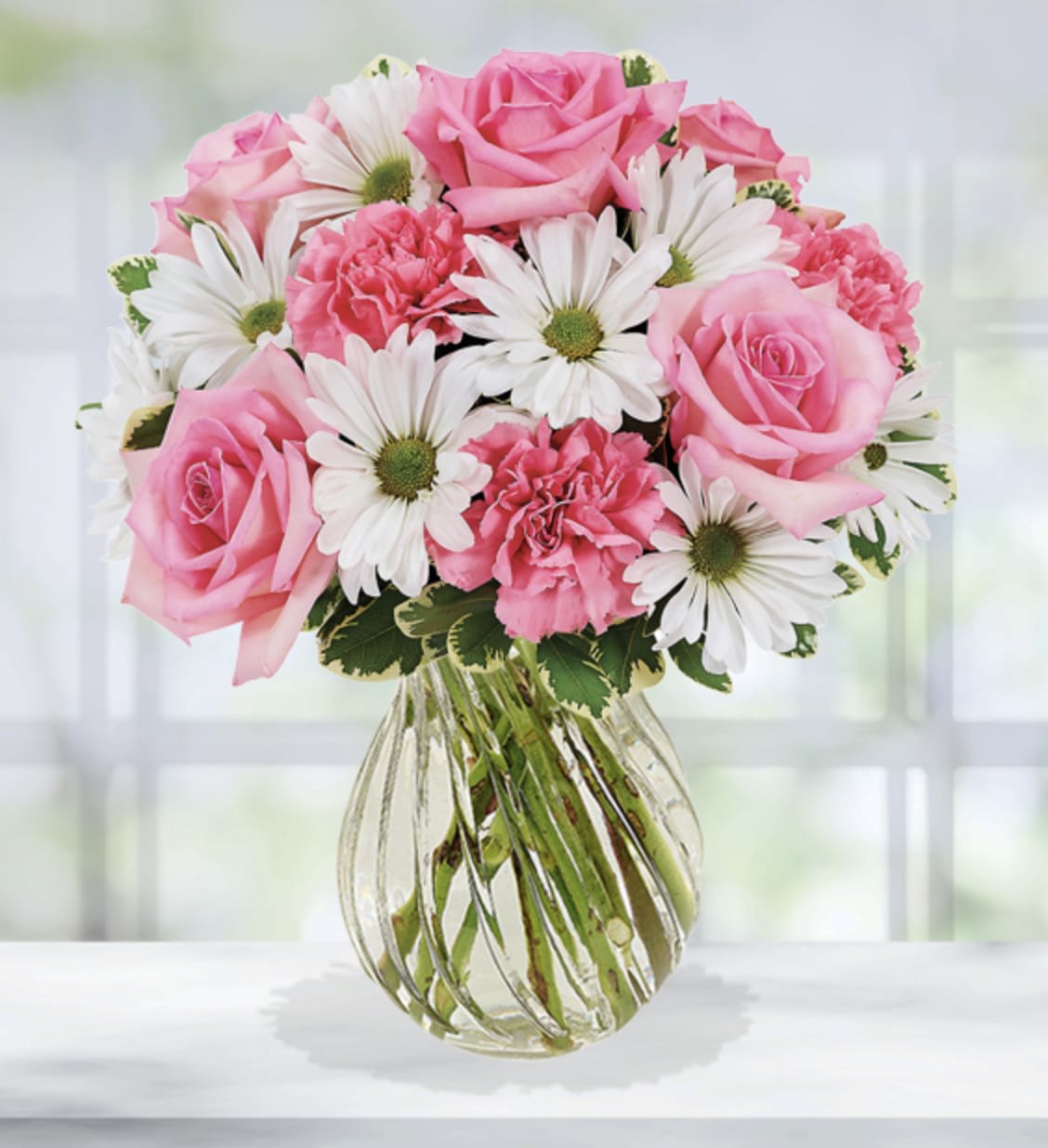 Sweet Surprises Bouquet - Sending a Sweet Surprises Bouquet is an absolutely charming way to send your warmest sentiments. Carnations, roses, daisies and lush greens are sweetly situated in a classic clear vase. Perfect for welcoming a new baby girl or any special occasion, this bouquet will delight your lucky recipient at every turn.  Item pictured is a depiction of an arrangement that we will make as similar as possible with the same look and feel.