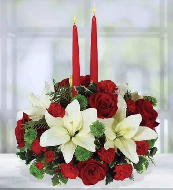 Christmas Dreams Centerpiece - There's nothing better than spending time with family and friends during the holidays and eating a delicious holiday meal. This centerpiece is the perfect accent to your holiday table! Your guests will marvel at the festive mix of deep red elegant roses, carnations and white lilies. Hand-designed by expert florists, this arrangement is a feast for the eyes. 