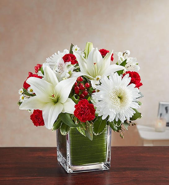 Healing Tears™ Red &amp; White - The color most related the heart, let red serve as a reminder that they will live forever in the hearts of loved ones. Our sympathy arrangement of timeless red roses, carnations, and white lilies, expertly gathered together in a clear glass cube lined with a Ti leaf ribbon, it is an exquisite gesture of comfort and healing.  Arrangement of red roses, hypericum and mini carnations and white Asiatic lilies, cremones, Alstroemeria and monte casino; accented with fresh greenery Artistically designed by our florists in a classic clear glass cube lined with a Ti leaf ribbon; vase measures 5"H x 5"D Large arrangement measures approximately 11"H x 11"L Medium arrangement measures approximately 10"H x 10"L Small arrangement does not include roses and measures approximately 9"H x 9"L Perfect gift for delivery to the homes of family members or friends Our florists hand-design each arrangement, so colors, varieties, and container may vary due to local availability Lilies may arrive in bud form and will open to full beauty over the next 2-3 days
