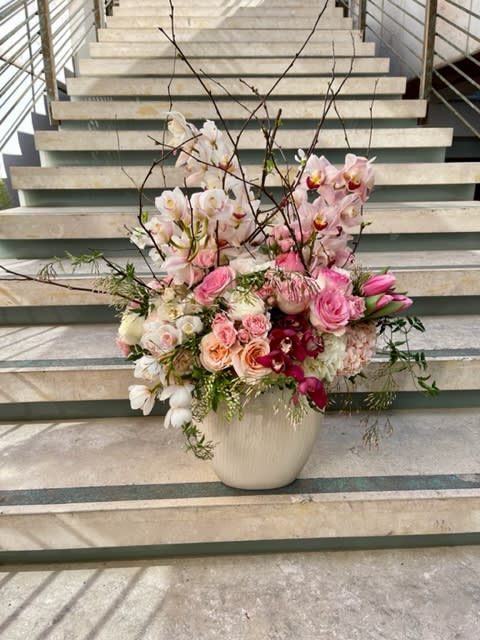 Elegant Romance Symphony: A Harmonious Fusion of Orchids, Roses, and Blooms - Embark on a journey through the world of refined romance with the &quot;Elegant Romance Symphony&quot; – an arrangement that harmoniously melds the exquisite beauty of Cymbidium orchids, roses, garden roses, hellebore, freesia, lilac, and spray roses. This masterpiece of floral artistry captures the essence of love and elegance, blending diverse blooms to create a breathtaking symphony of romantic charm.   &quot;Varieties and colors of flowers may vary according to season and availability.&quot; This arrangement includes a newly cleaned vase and good quality water &amp; flower food.  Item: 345  Care Instructions: For the best vase life, change the water every two days.