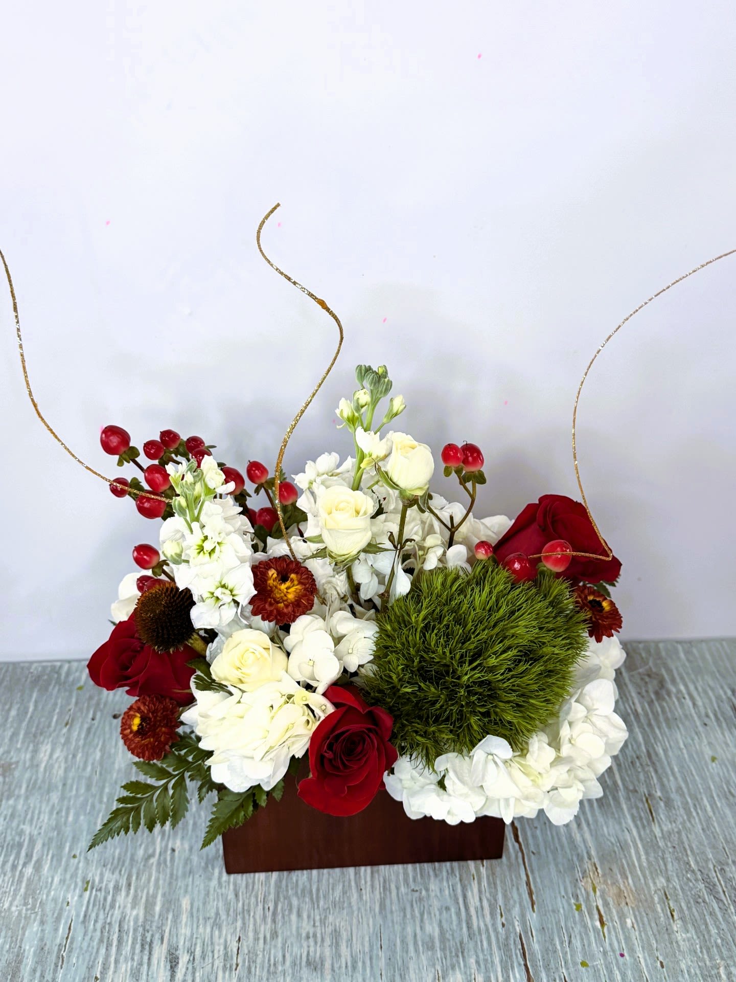 Christmas #1 - White, red and green arrangement with hints of gold and yellow. Designed in a cherry color wooden container.