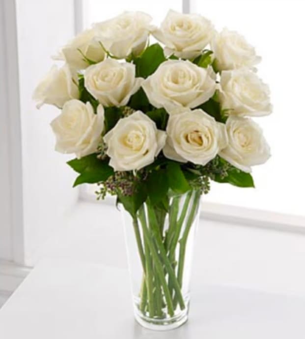 Dozen White Roses - A dozen white roses delivered in a clear glass vase with minimal greens and filler flowers to highlight these beautiful white roses. Vase and greenery may vary.