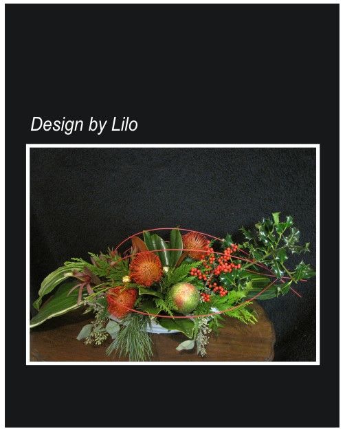 Holiday Enchantment Center Piece - Christmas greenery and non-traditional greenery surround this wonderful center piece that includes Protea a large holly branch, magnolia leaves in a ceramic container, with decorations to compliment this wonderful design. Always fresh for Christmas and designed by Lilo Kallai   Approximately: 15&quot; round