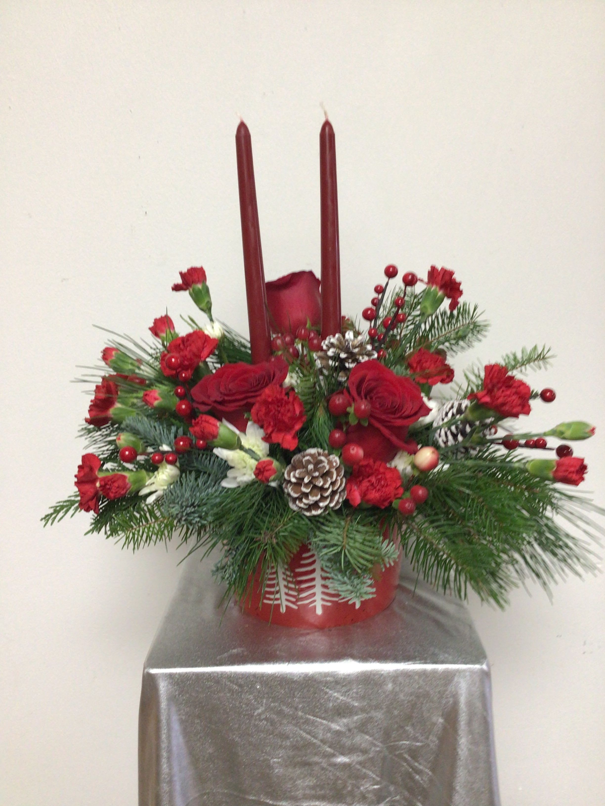 Holiday Centerpiece - Tree embossed ceramic bowl is 4 inches tall and 6 inches wide and arranged with red miniature carnations, white carnations, white snowflake mums, red roses, white frosted pine cones, red berries and mixed evergreens. This is an all around arrangement and approximately 12 inches tall by 16 inches wide.
