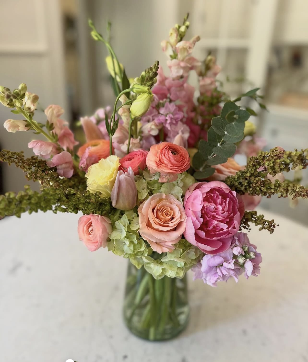 Pastel Spring Garden - Spring into this beauty filled seasonal spring favorites including tulips, ranunculus, lisianthus, stock and hydrangeas in soft pinks, peaches, and green. Peonies will be substituted with a flower of same value if not in season. 
