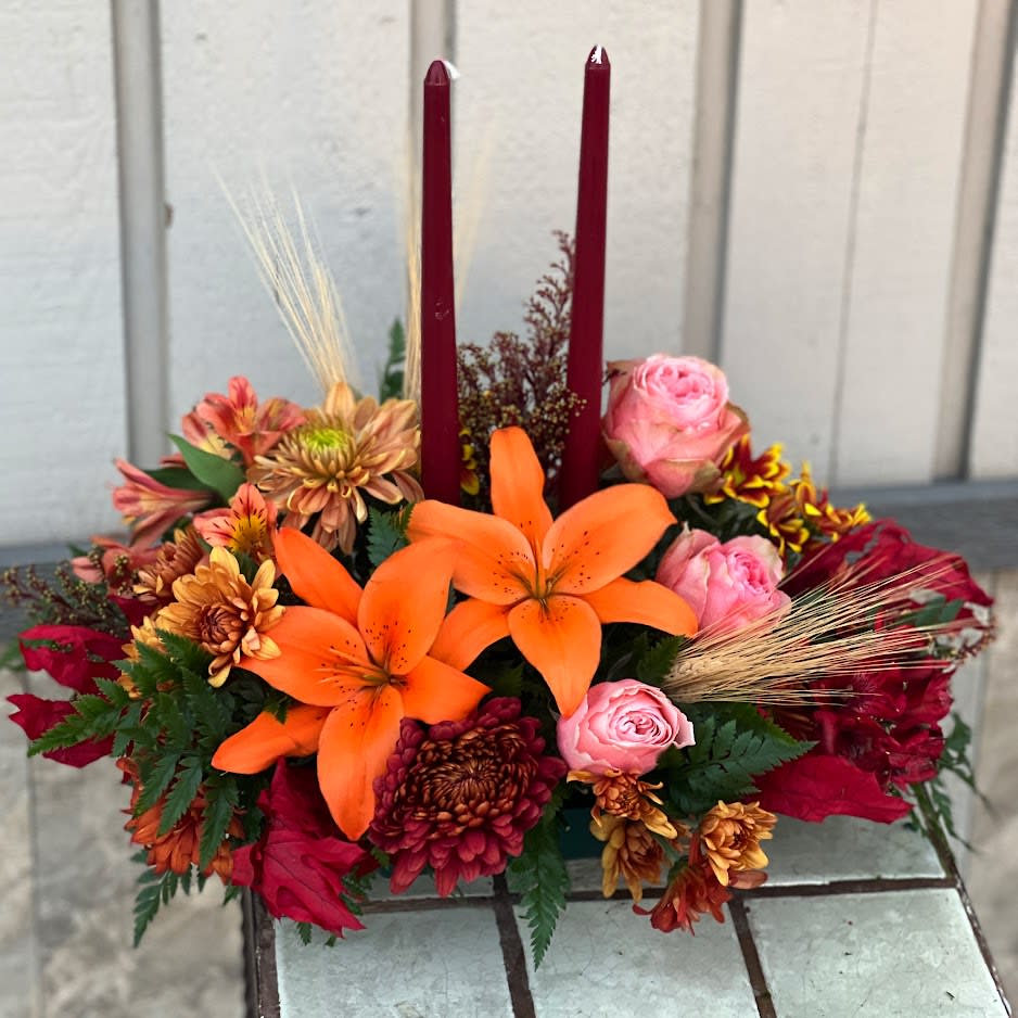 Family Gathering - As your loved ones gather around the table, they'll bask in the warm glow of two orange taper candles surrounded by a fantastic array of fall flowers.