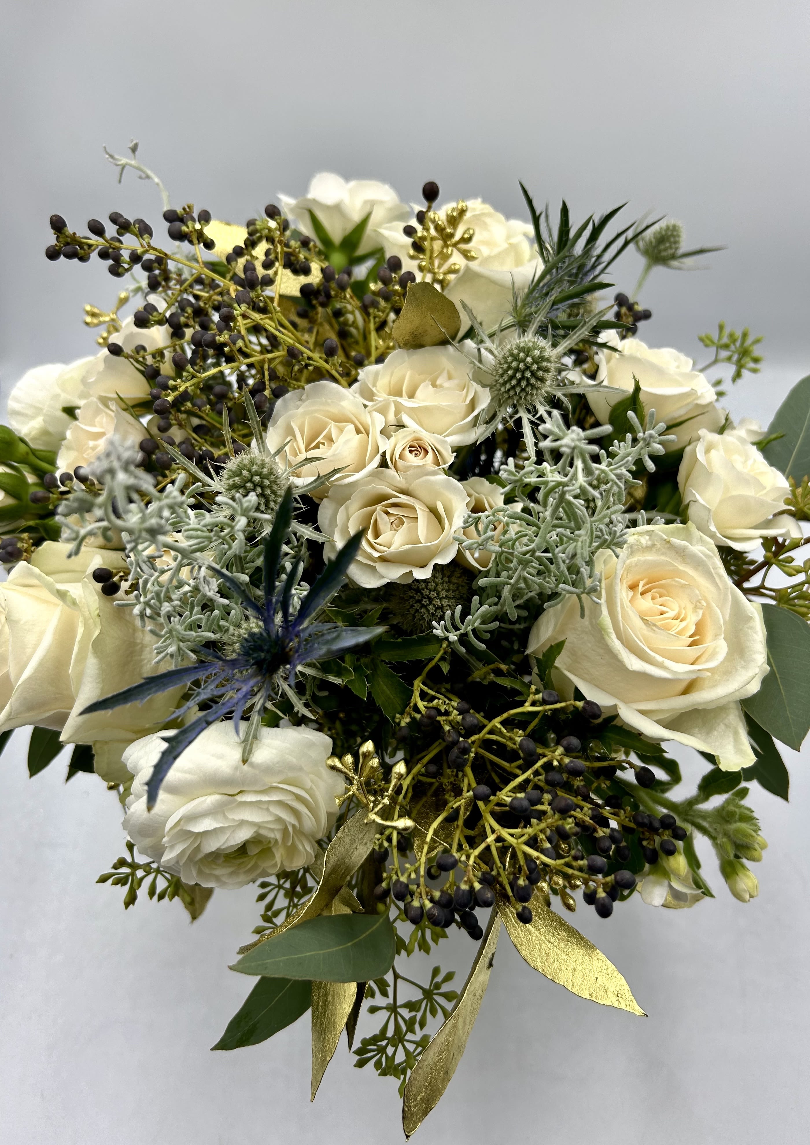  Little Bit Glitz! - What's more fun that regular fresh flowers? Flowers with little bit of glitz!  Whites, greens, frosty greens and a hint of blue/purple mixed with just the right amount of metallic flocked eucalyptus.  It is such a beautiful combination set in our frosted glass or white glass vase.  We use premium flowers such as ranunculus, spray rose, roses and you may be pops of thistle &amp; seasonal berries.  It is so beautiful and adds that pop of fun.    Standard size is a 4x4 glass vase with silver interior - Kitchen table/Gift/coffee table, dresser, office - $79.50 - If you would like black glass instead let us know in the notes.  Deluxe size comes in a 6x6 frosted or white glass glass vase - Kitchen/dining table, coffee table, gift, - $139.50 Premium size is super robust in a white frosted taller vase with more flowers &amp; will include hydrangea and snapdragon or stock + a few white branches - kitchen island, foyer, office gorgeous glammy gift- $289.50
