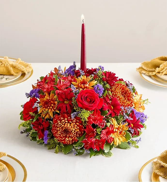 Brilliant Autumn™ Centerpiece - All-around centerpiece arrangement with red roses, Peruvian lilies (alstroemerias), and daisy poms; bronze mum disbuds and cushion poms; purple limoniums and statices; and solidago, accented with assorted greenery Premium arrangement features two 12&quot;H burgundy taper candles; measures approximately 12&quot;Dia Deluxe arrangement features one 12&quot;H burgundy taper candle; measures approximately 11&quot;Dia Standard arrangement features one 12&quot;H burgundy taper candle; measures approximately 10&quot;Dia