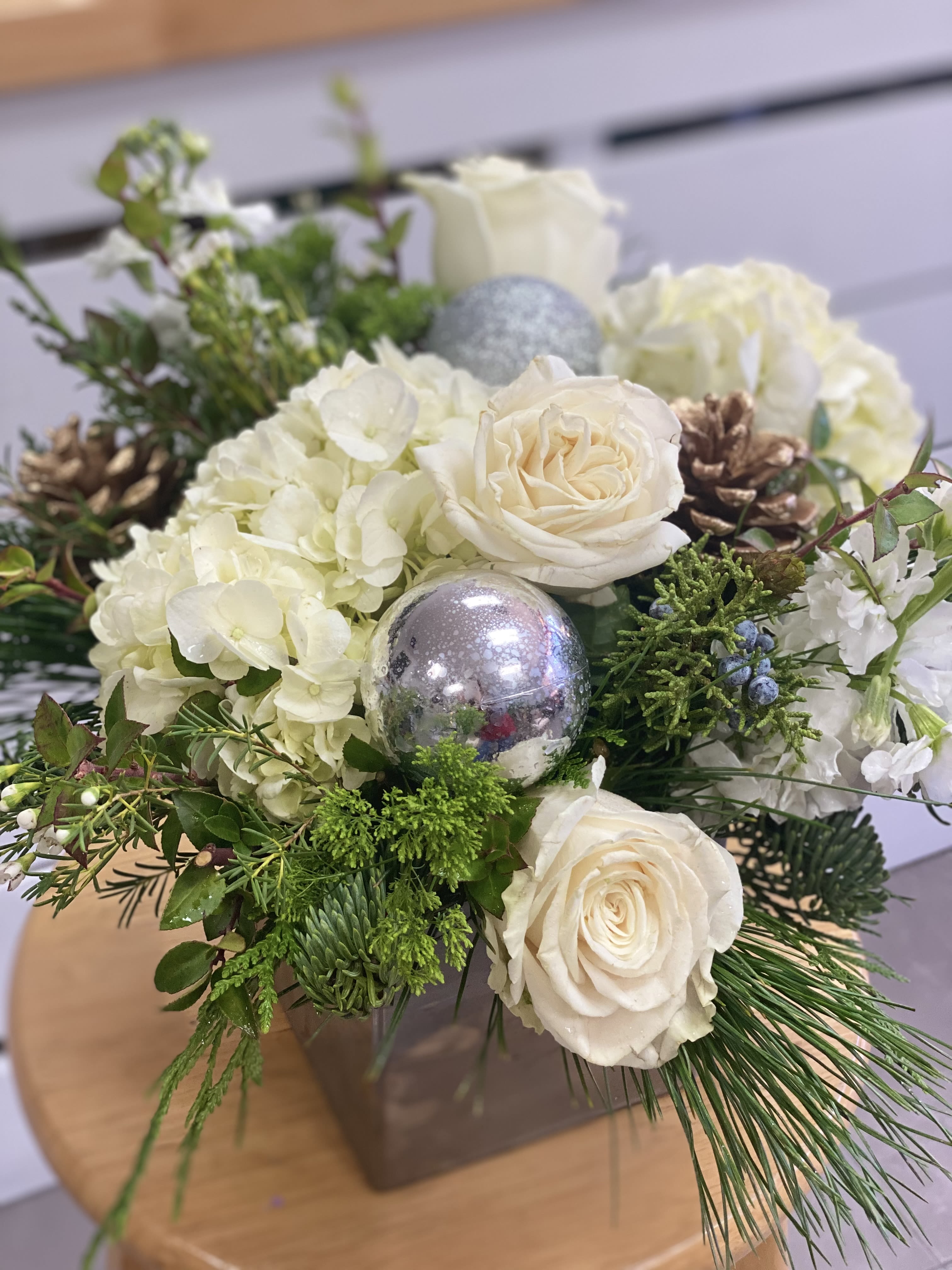 Silver Bells - Silver cube or cylinder (if available) with white and green flowers, ornaments, pinecones, christmas greens