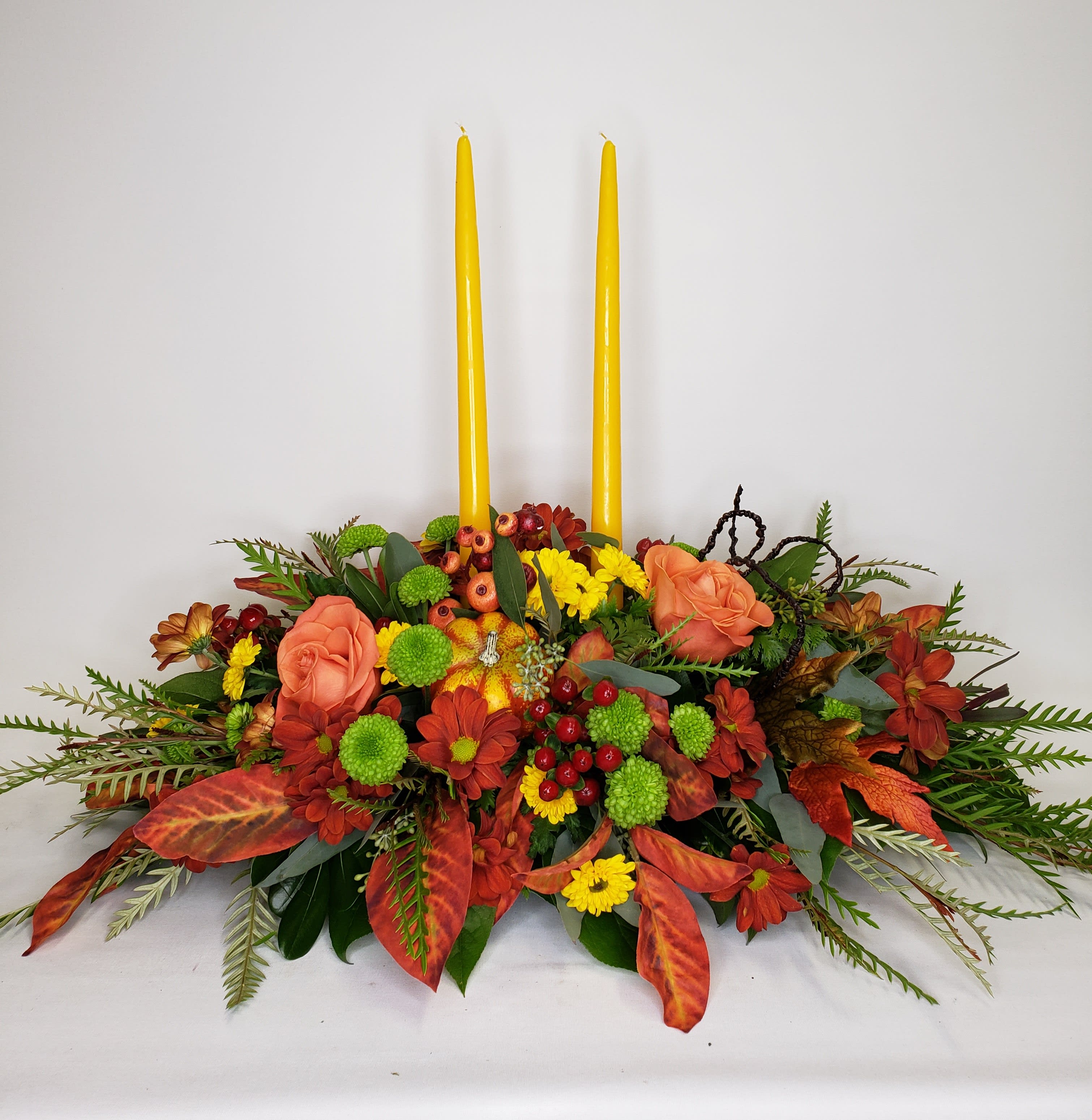 Autumn Bounty - A lovely mix of roses and fall flowers make the perfect centerpiece to gather around. Candle color will be either red or yellow depending on availability. You can request with out candles and we will add additional flowers instead. 