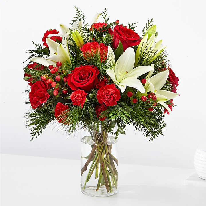 Joyful Greetings - This beautiful vase arrangement filled with red roses white lillies, carnations and holiday greens. 