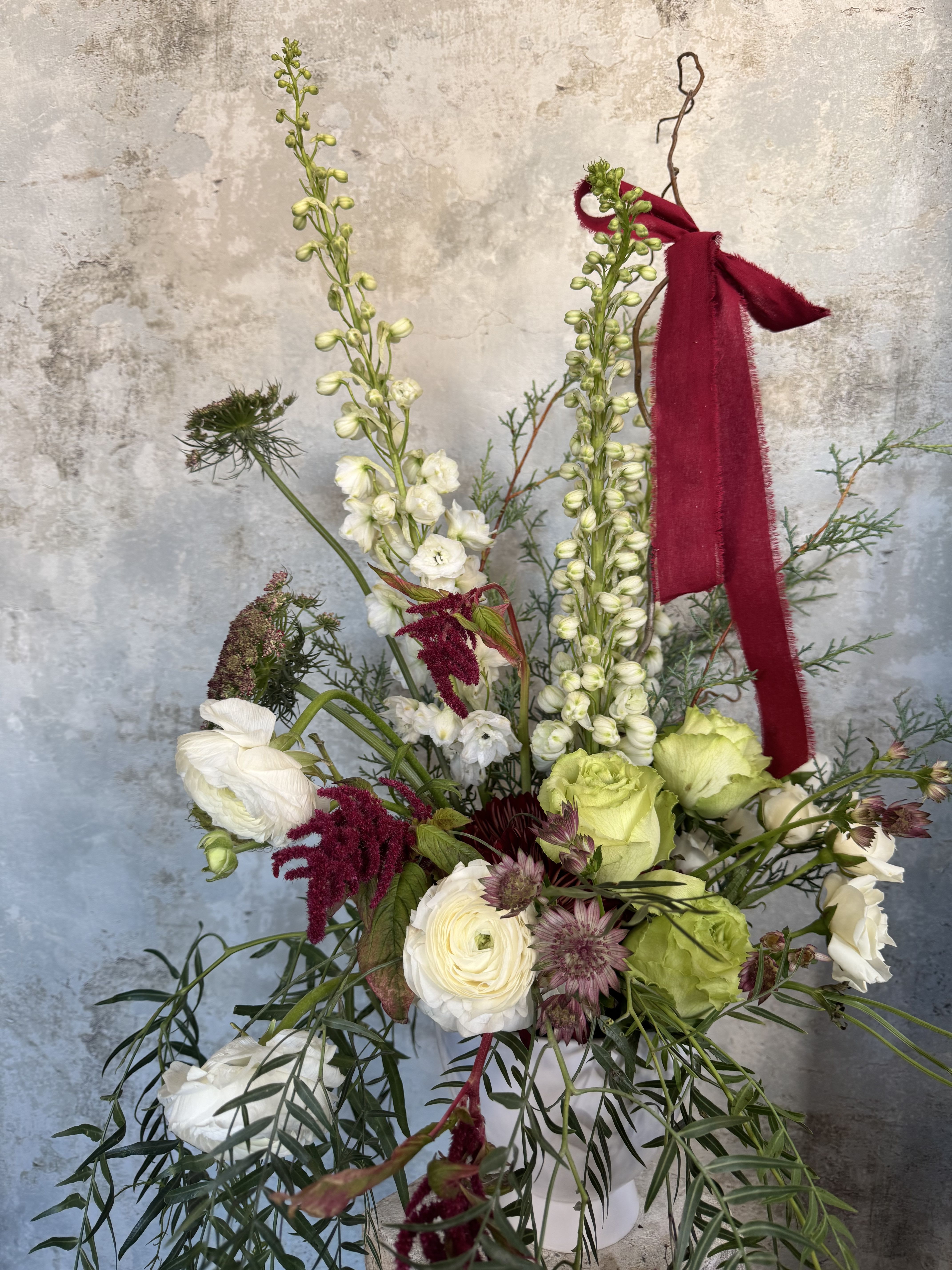 Not-So-Traditional Winter Arrangement - This season, we're bringing a little extra sparkle to your celebrations with our not-so-traditional winter arrangements. If you're looking for something unique, we’ve got you covered. Each arrangement features a fun mix of seasonal blooms, hand-picked for their beauty and character. You can choose how you'd like your flowers to be presented: wrapped loosely for that relaxed, organic vibe, arranged neatly in a classic vase, or displayed elegantly in a stunning compote container. Each arrangement is one-of-a-kind!  If you'd like to add that extra bit of charm, you can request a beautiful bow to top off your arrangement, giving it the perfect finishing touch. Whether it's for a gift or your own home, we’ll make sure your flowers feel as special as the occasion.   *Pictured is a premium size arrangement.