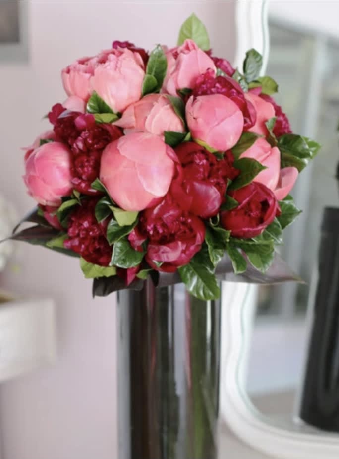 PEONY BLOOMS  - CORAL AND BURGUNDY PEONIES ARE DESINED IN A TALL TE LEAF LINED VASE . THE DELICATE PETALS OF THE PEONY WILL BLOOM RIGHT BEFORE YOUR EYES.
