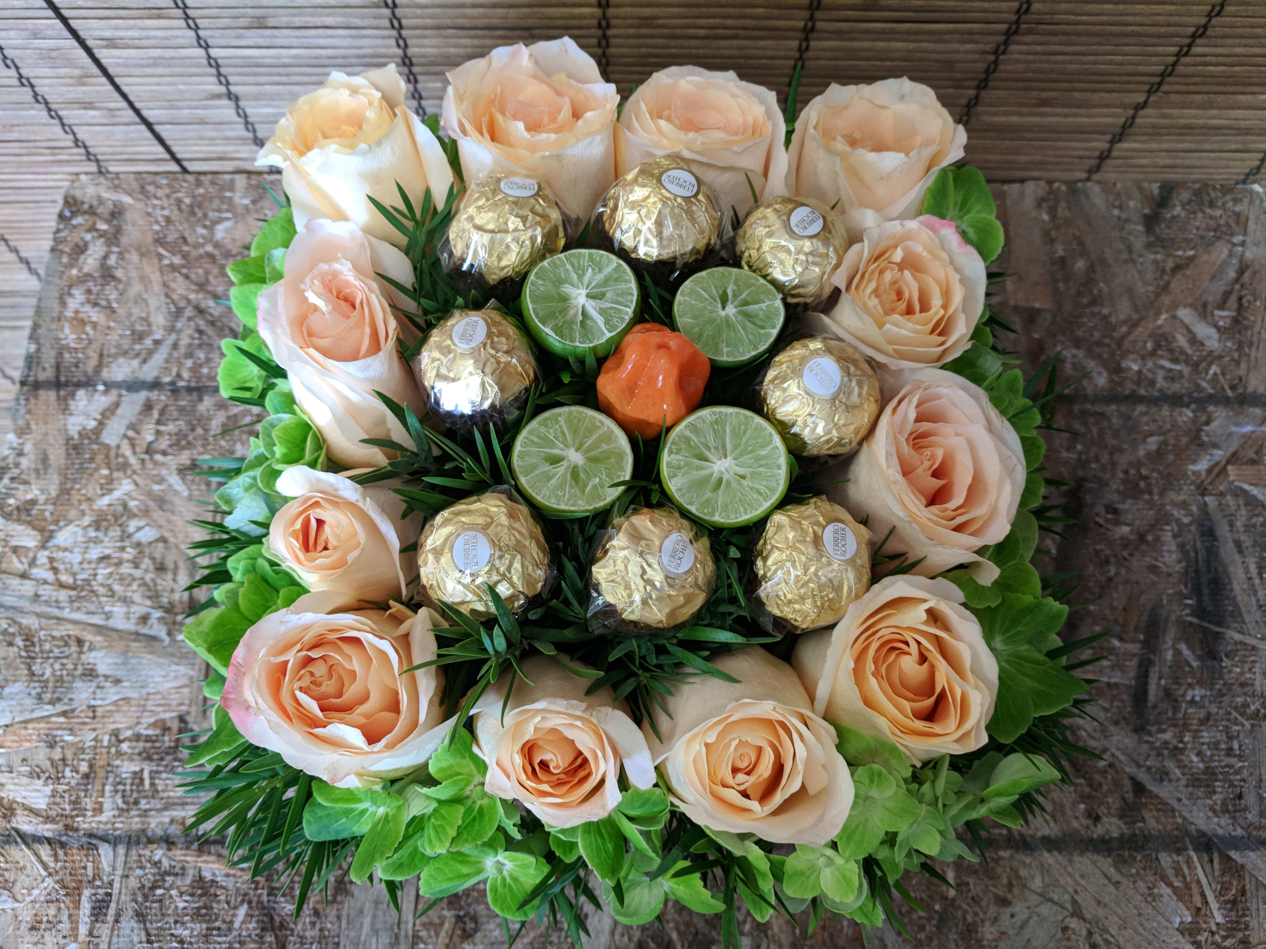 LIME  Splash by Van Nuys Flowers - More than one dozen Peach Roses Surrounding  Limes, Ferrero Rocher Gourmet Chocolates, and  Green Hydrangeas, to Grace any Dinner Table,  or  Coffee Table  !  Perfect for any occasion