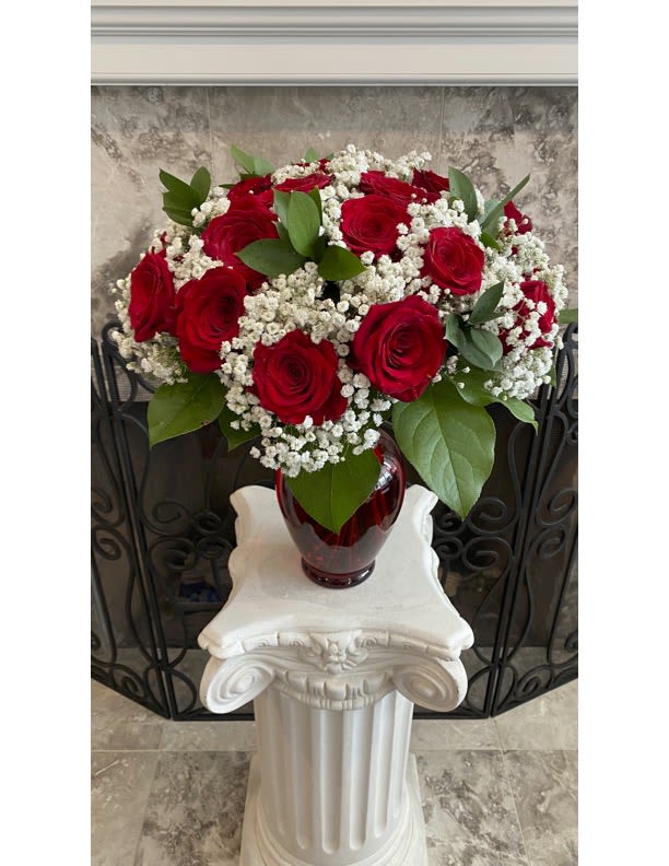 Premium Red Rose Bouquet In Red Vase - A lavish bouquet of two dozen enchanting red roses, interspersed with delicate baby's breath, graces a red glass vase, radiating love and romance. The abundant display of roses creates a visually stunning arrangement that captivates with its vibrant hues. Includes:• Two Dozen Red Roses • Baby's Breath• Red Glass Vase• Complimentary Gift Message 16''H 16''W      And will be delivered approximately as pictured.