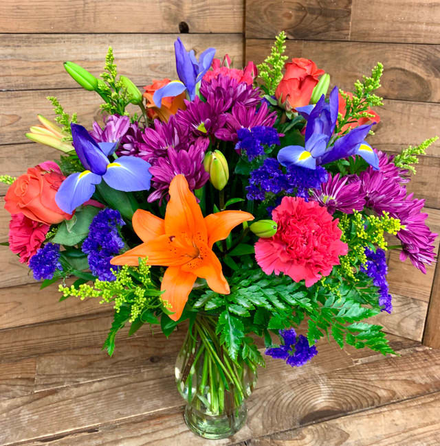 Meet me in Paradise - Meet me in Paradise A dazzling gem of an arrangement in the vibrant tones of the season – pops of hot pink, orange, purple, and green – are luminous in this magnificent piece. Arrangement includes Asiatic lilies, orange roses, blue iris, purple daisies, hot pink carnations, purple statice and mixed greenery.