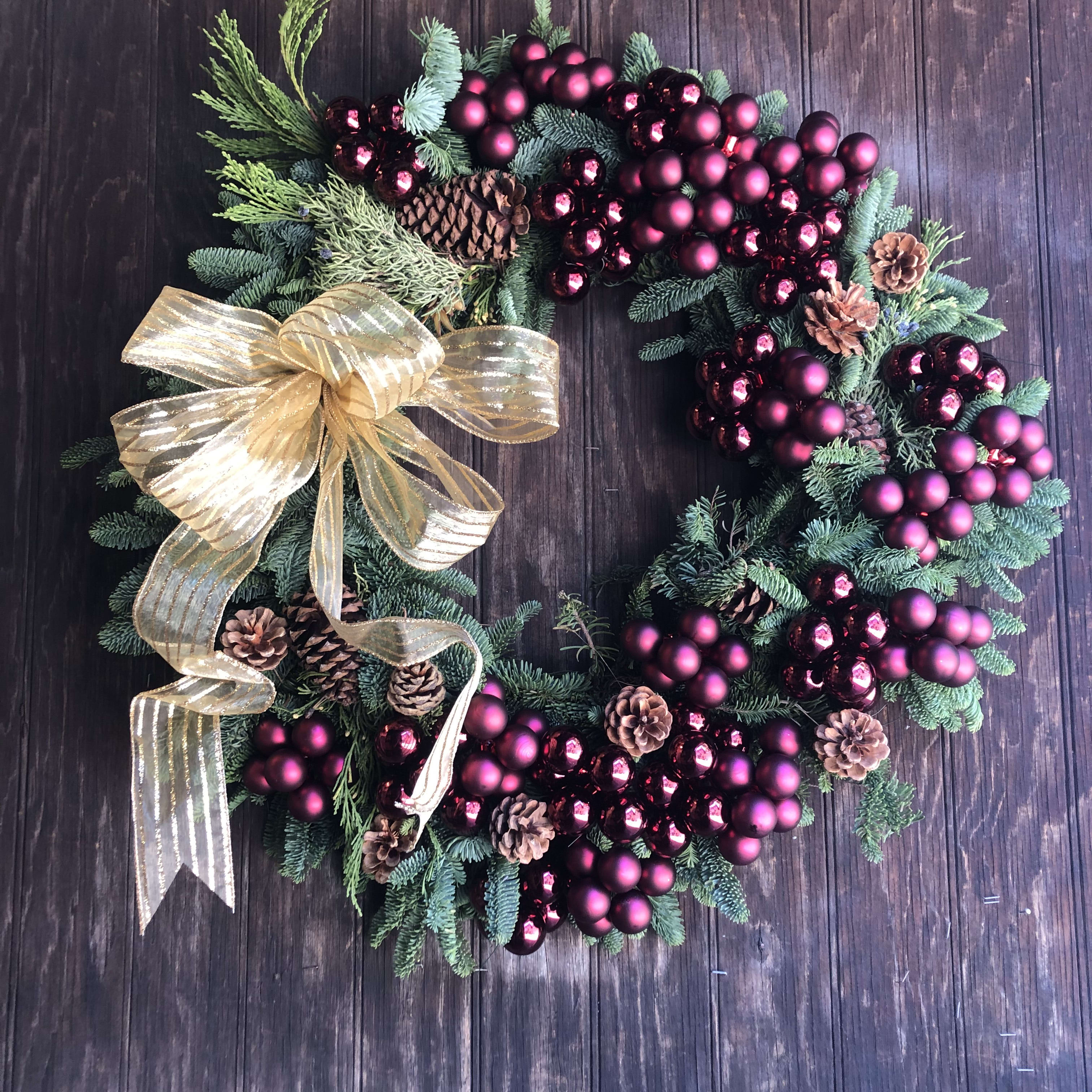 Santa Baby Wreath 24&quot; - Mixed natural greens wreath. Millimeter balls in a wide variety of color options, pine cones. Pretty ribbon bow. Pictured are millimeter balls in reds, burgundy. Other color options include silvers, golds, purples, greens, endless possibilities, based on availability.
