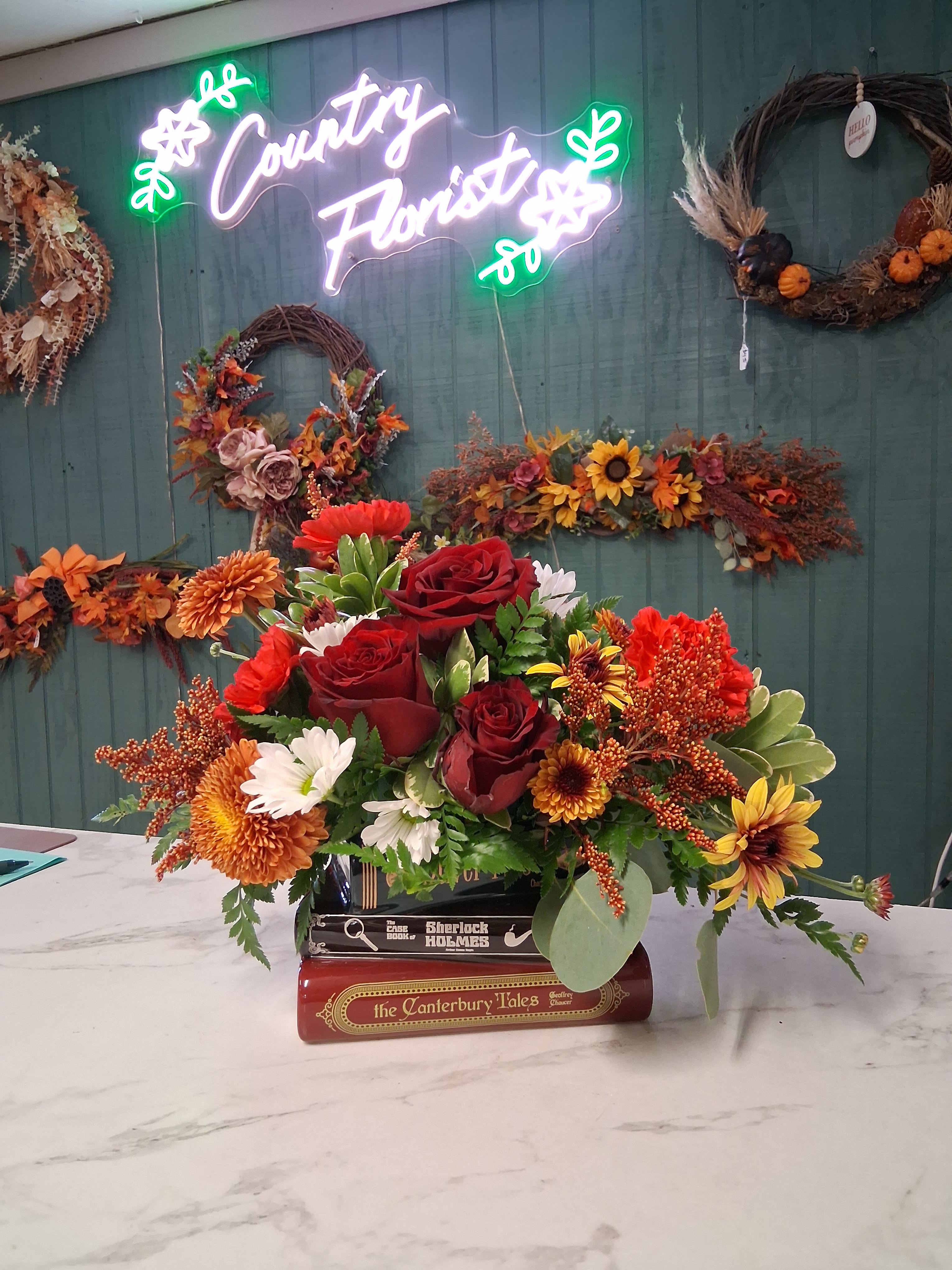 Oliver Twist - Full of character and classic charm, our Oliver Twist arrangement is a true storybook delight. Designed in a beautifully detailed ceramic book stack featuring Oliver Twist, Sherlock Holmes, and The Canterbury Tales, this bouquet overflows with rich, seasonal blooms inspired by the warmth and wonder of autumn. It’s a perfect gift for book lovers, vintage souls, or anyone who appreciates a touch of literary whimsy paired with the natural beauty of fresh flowers. Once the flowers have faded, the keepsake container makes a charming decorative accent or a unique spot to store trinkets and treasures.  Please note: Flowers and colors will vary based on seasonal availability. If you have specific preferences, kindly include them in the “Special Instructions” section when placing your order.