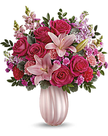 Rosy Swirls - Capture Mom's heart with our pearlescent Teleflora's Rosy Swirls vase, radiating elegance and charm, paired with a bouquet of pink roses and lavender blooms, a delightful Mother's Day surprise she'll cherish. Create magic for Mom with Teleflora's Rosy Swirls vase, complemented by a bouquet of hot pink roses, pink asiatic lilies, light pink and hot pink carnations, miniature carnations, pink snapdragons, light pink stock, raspberry sinuata statice, huckleberry, and dusty miller, a radiant Mother's Day surprise she'll cherish. Orientation: All-Around