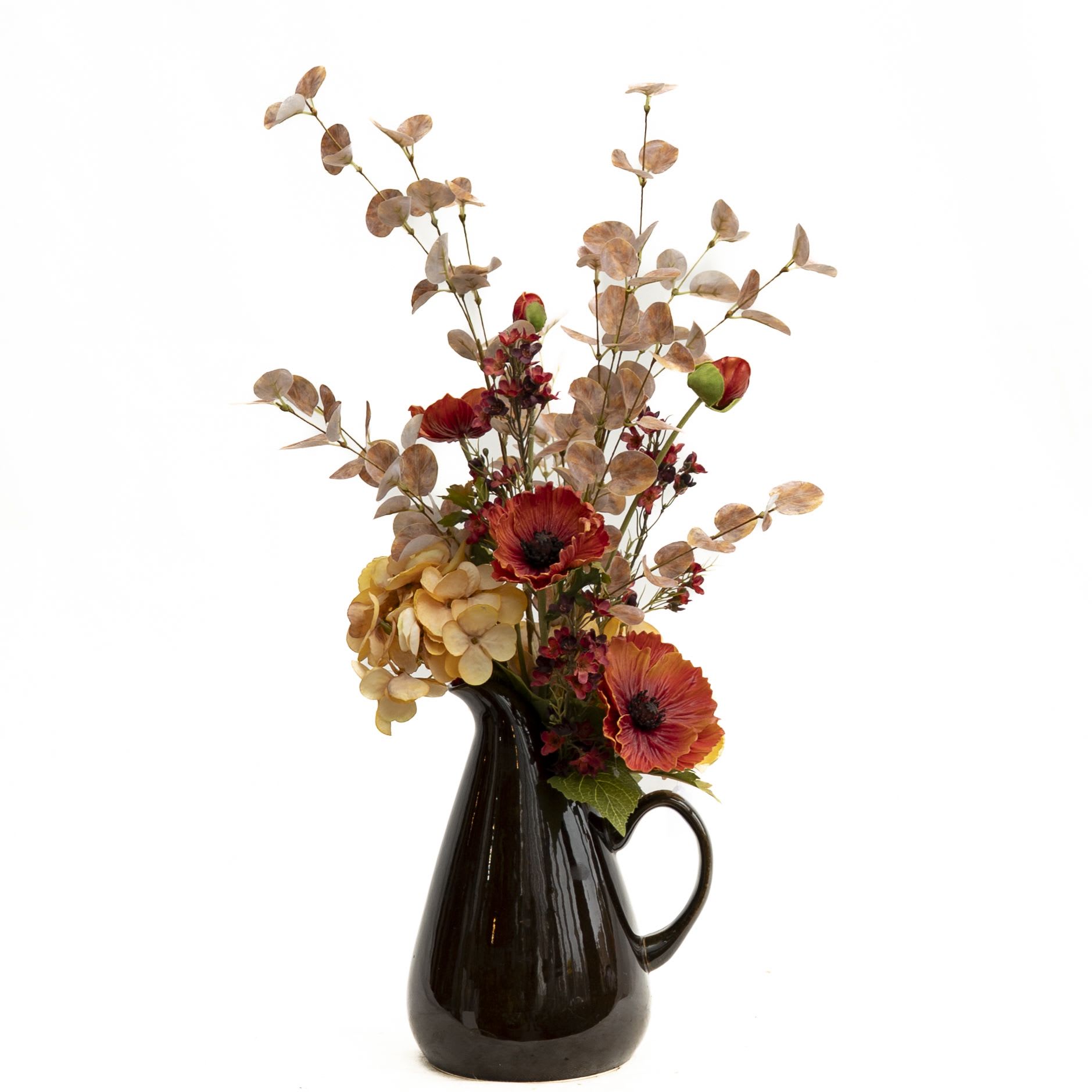 Autumn Fields Pitcher (artificial) - Rustic charm meets natural elegance in the Autumn Fields Pitcher. This one-sided artificial arrangement features warm-toned hydrangeas, deep orange anemones, and soft fall foliage gracefully arranged in a sleek brown ceramic pitcher. With its earthy hues and airy branches, it brings a touch of countryside beauty to any home décor—perfect for a mantel, entryway, or dining table centerpiece.